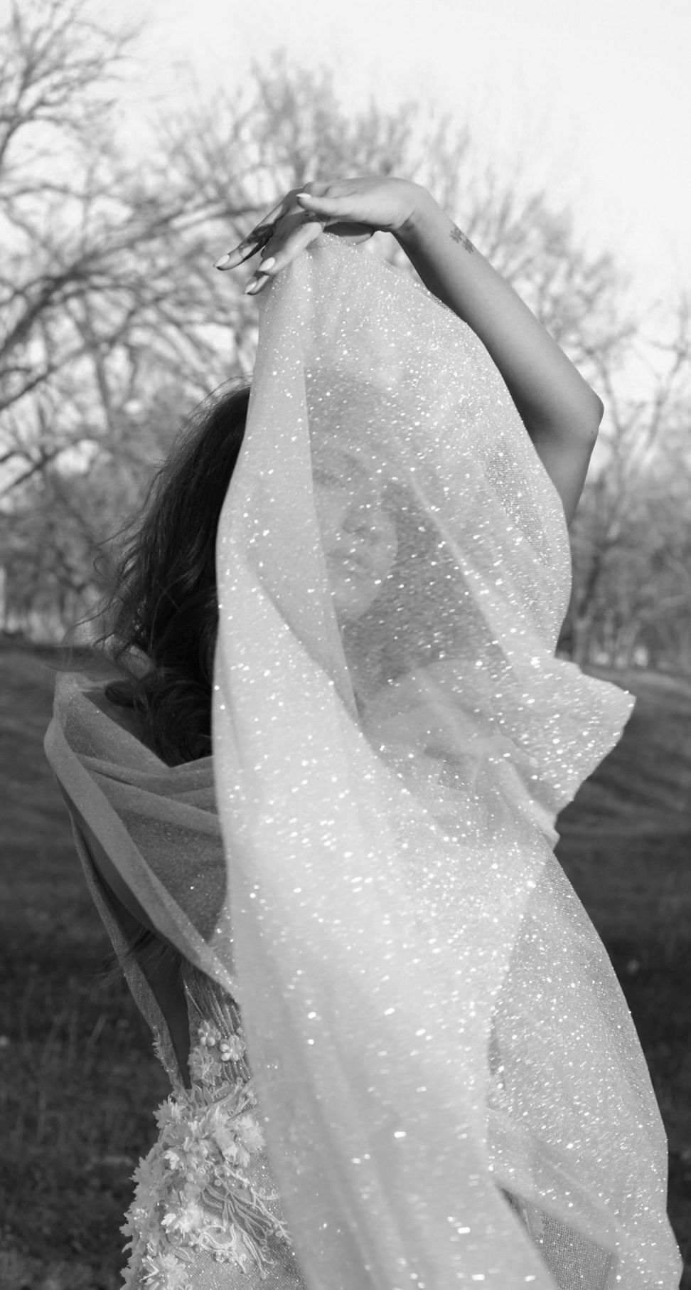 Ethereal bridal shot of sparkling white fabric flowing in the breeze against a winter landscape.
