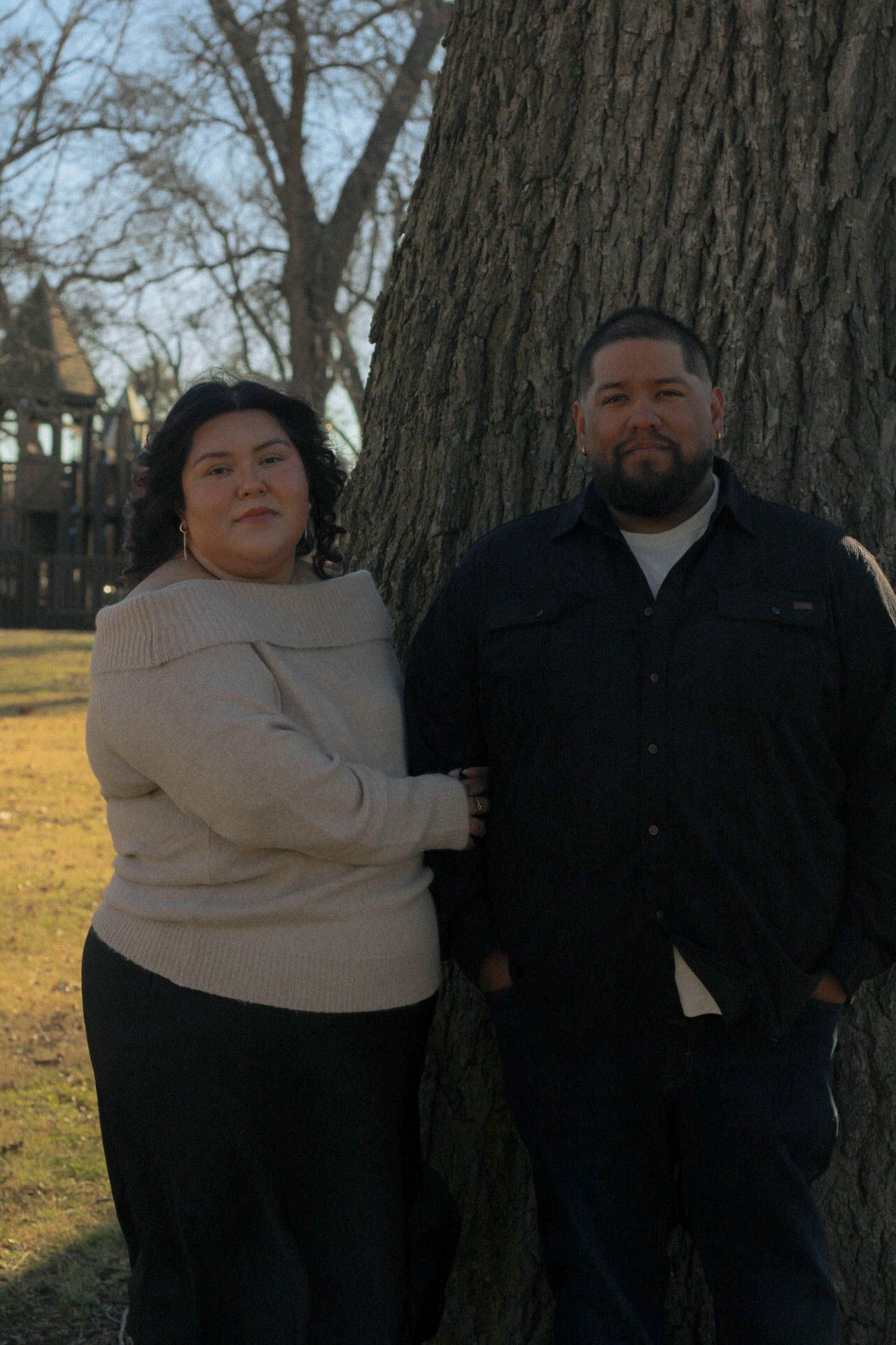 Casual outdoor portrait session near large tree in park.