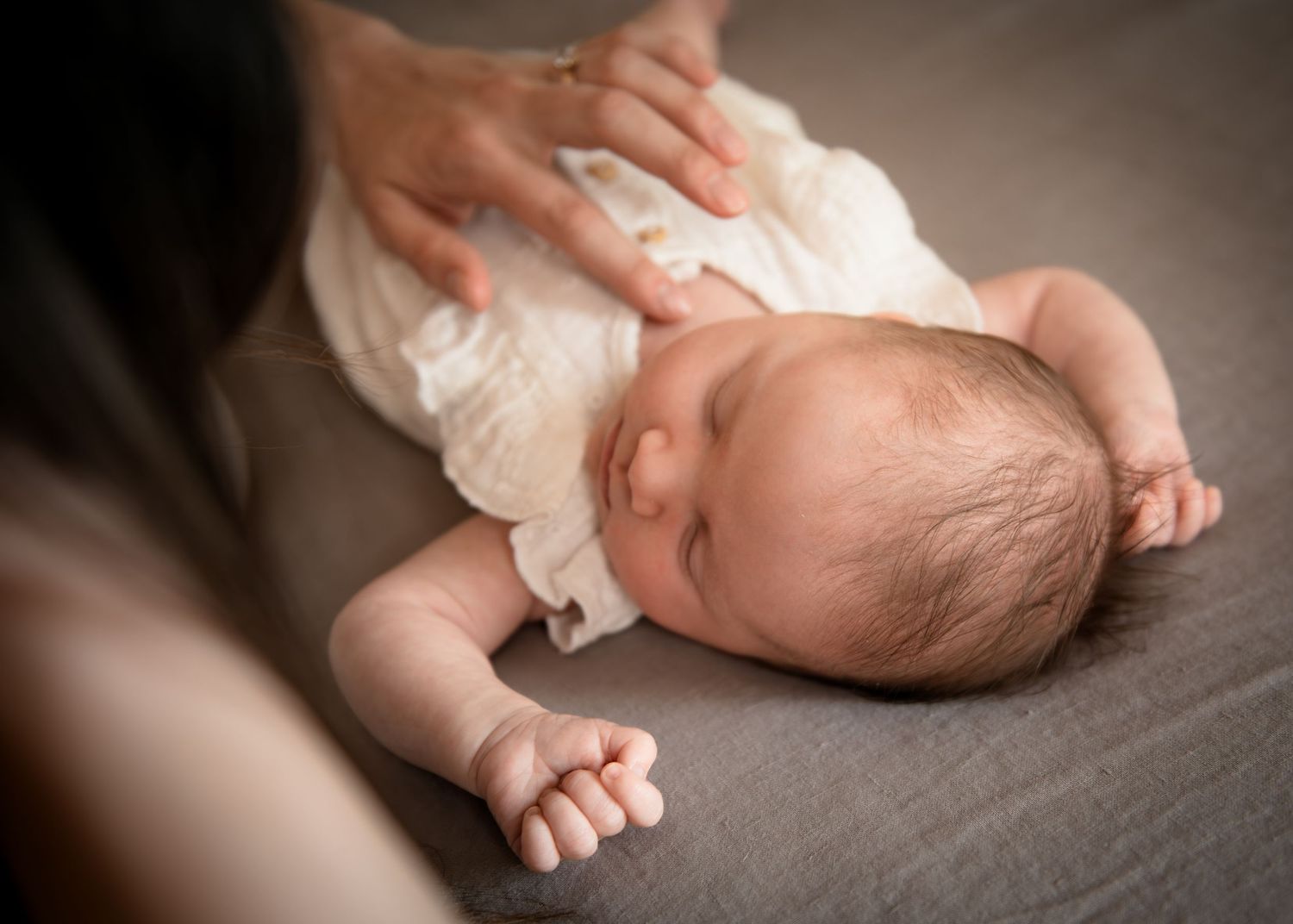 Peaceful sleeping newborn with tiny feet and hands in soft lighting.