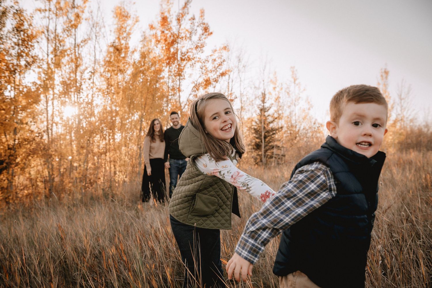 Family enjoying an autumn photoshoot together at Glenmore Reservoir in a field of tall golden grass during sunset.