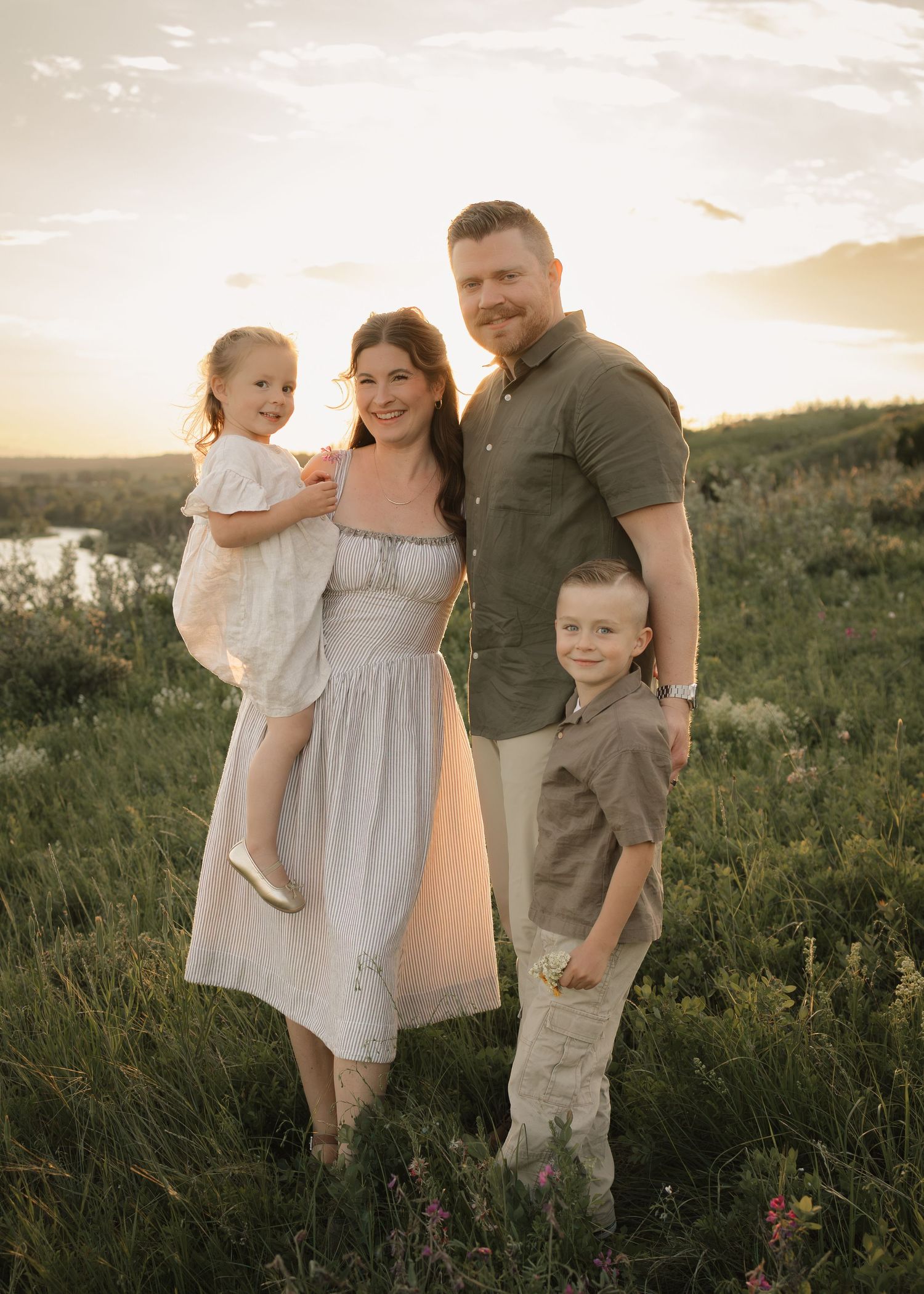 Family of four smiling at camera during Calgary photo session at golden hour