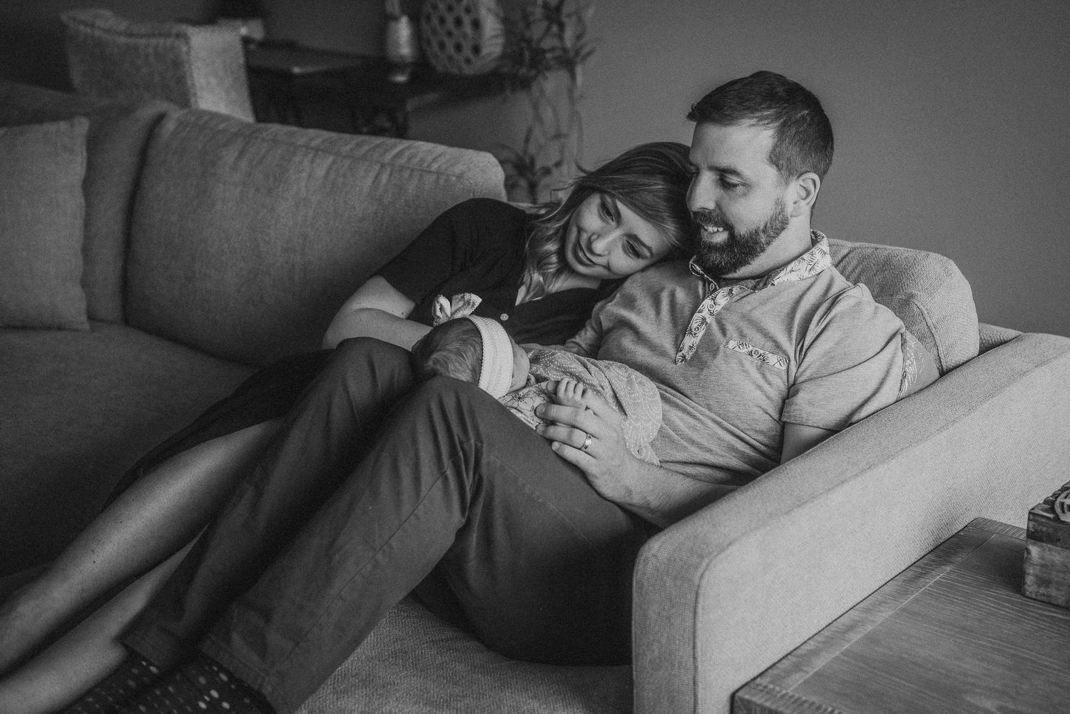 Black and white photo of couple cuddling and laughing on comfortable sofa.