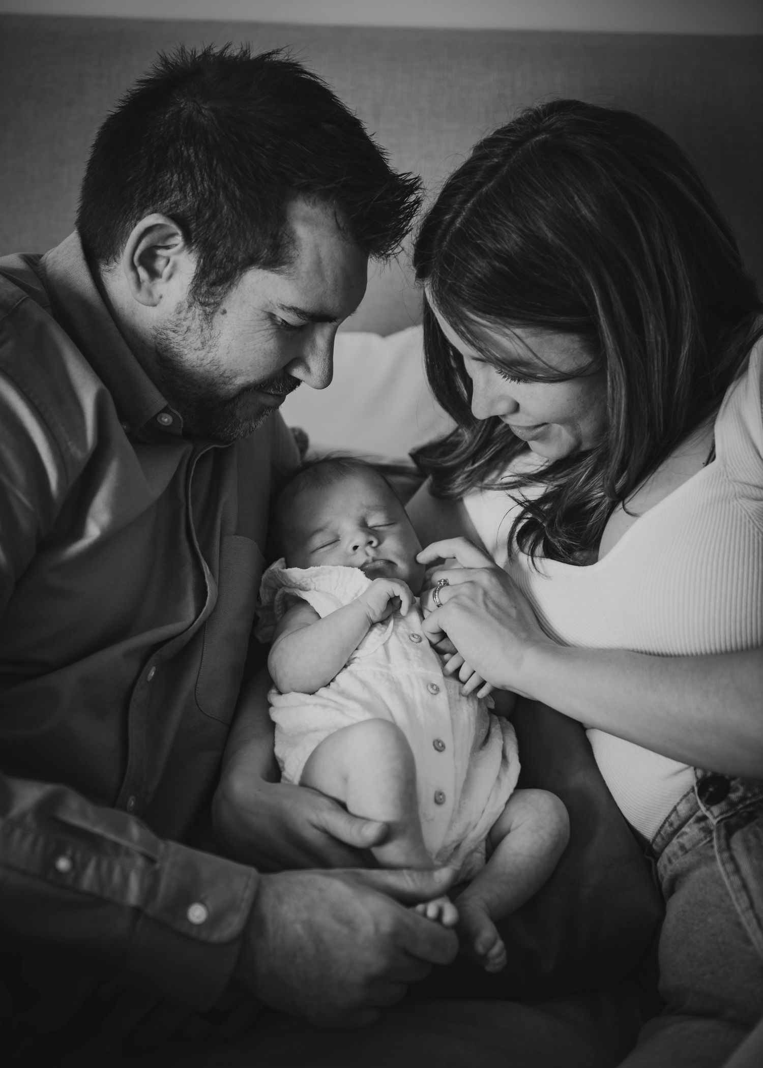 Black and white portrait of parents sharing an intimate moment with their newborn.
