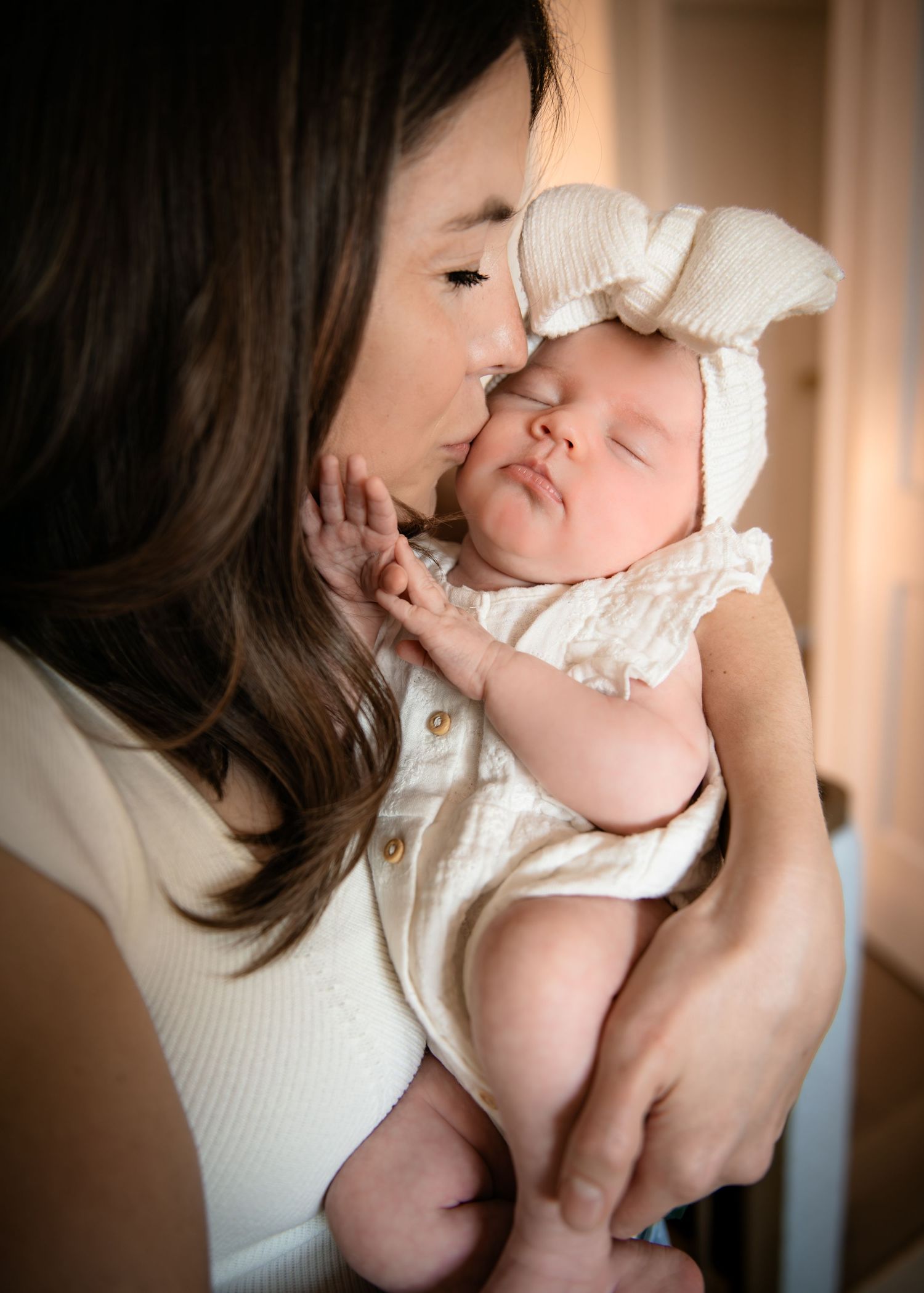 Tender moment between parent and baby in soft natural lighting.