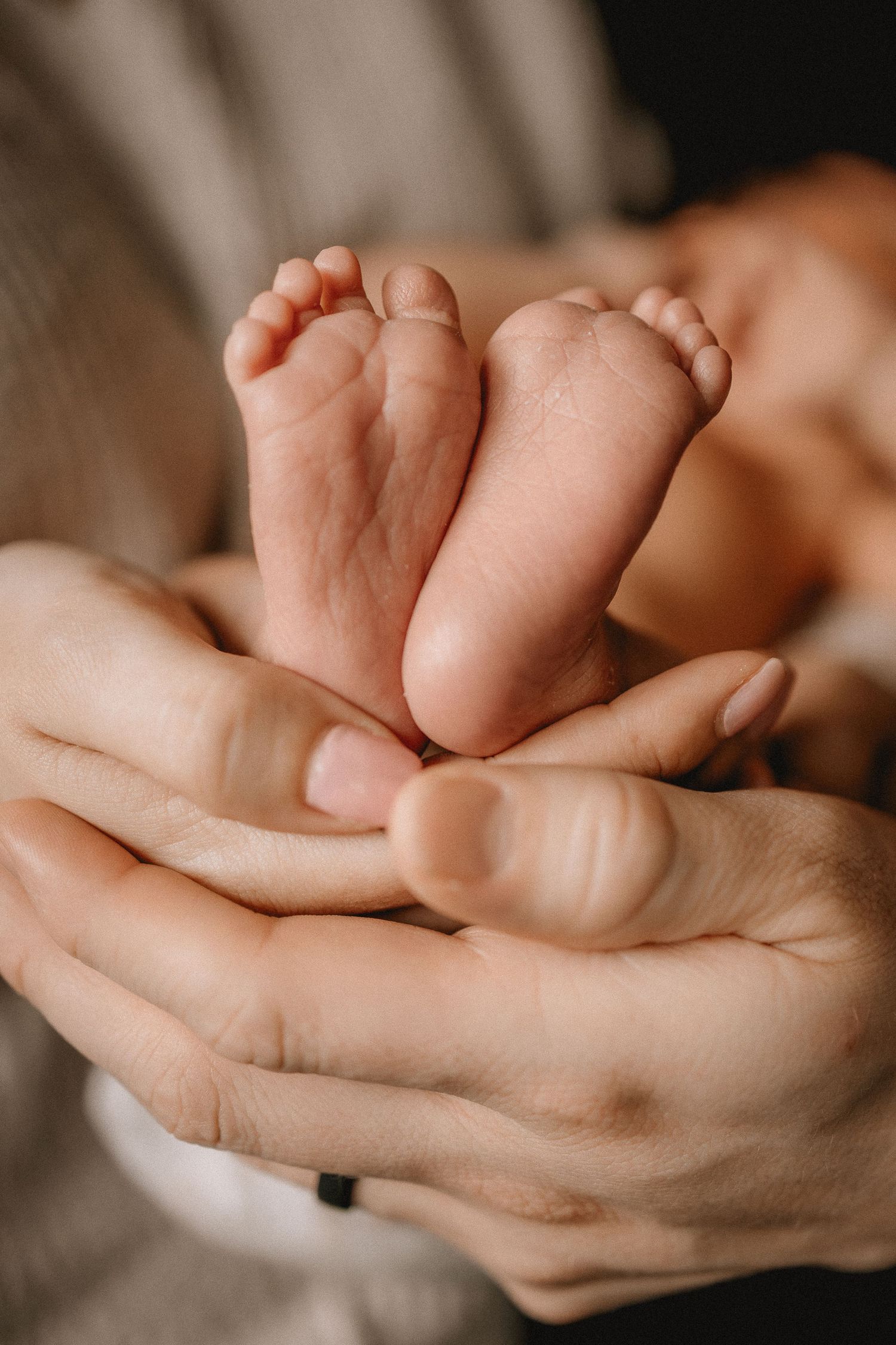 Tiny newborn baby feet cradled gently in the loving hands of their parents, close-up photography in Calgary