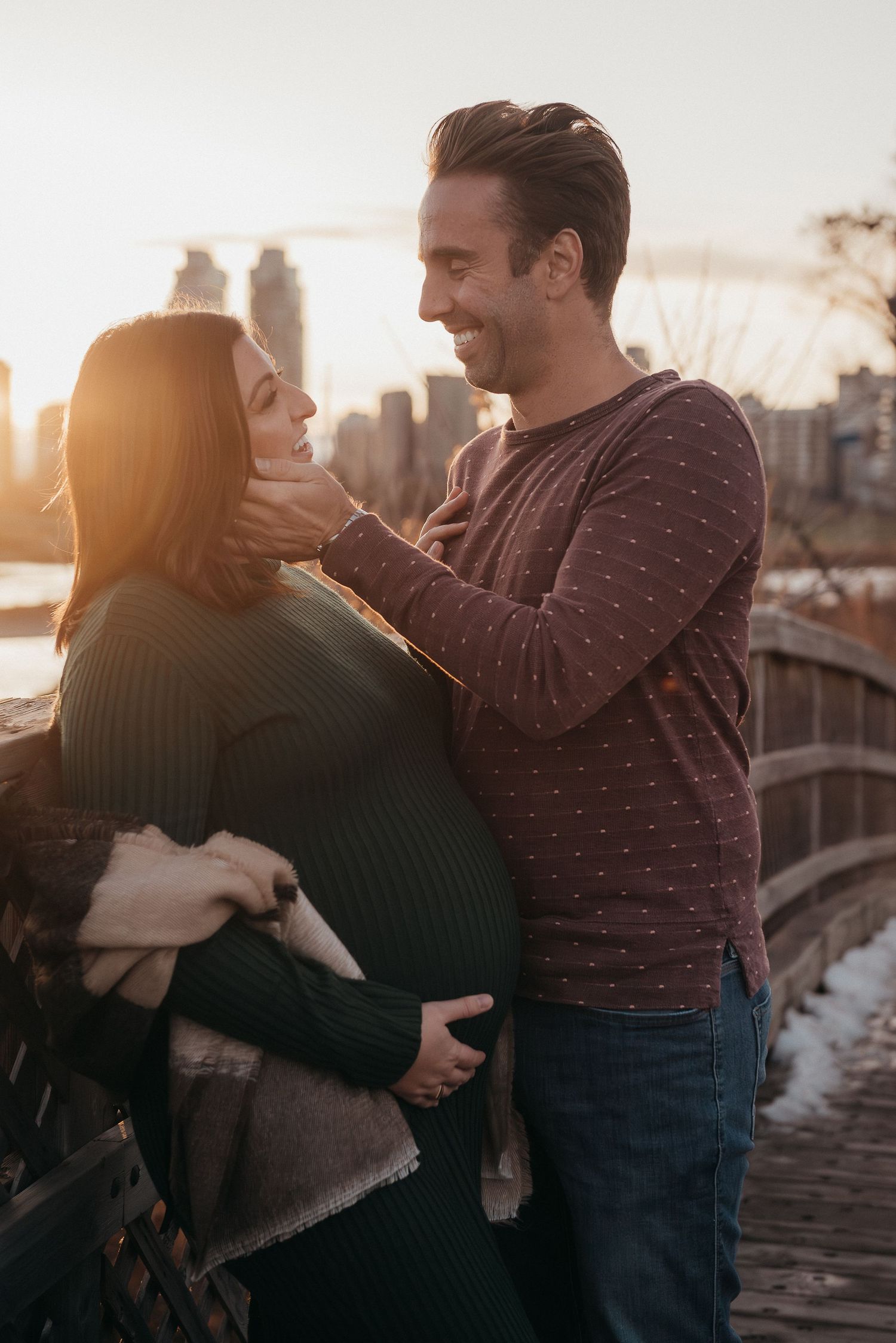 Romantic sunset photoshoot on a bridge with urban Calgary skyline backdrop.
