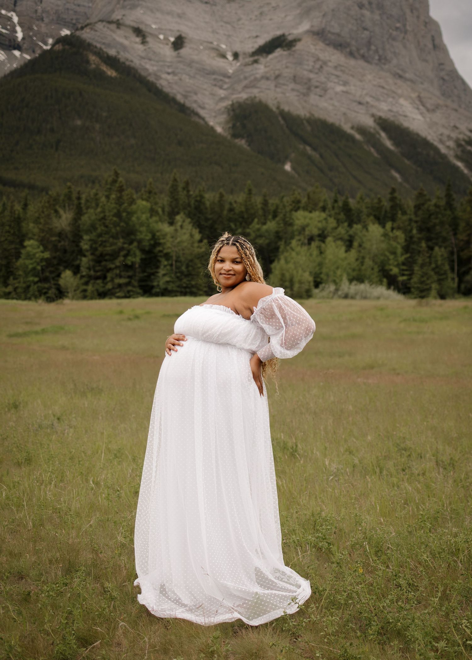 Pregnant mom looking at camera with her hand on her belly in open field