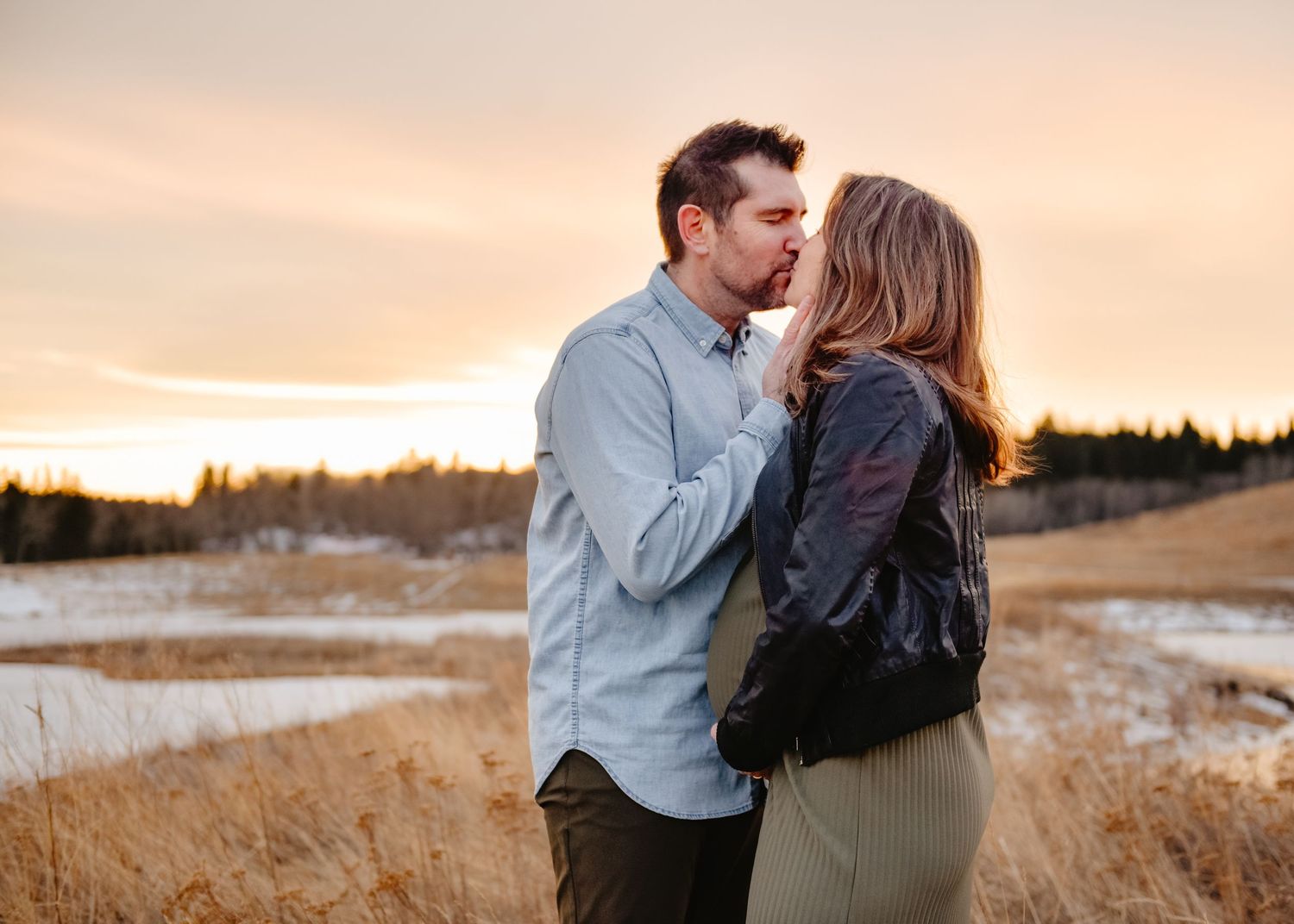 Intimate outdoor maternity session in a field at golden hour.