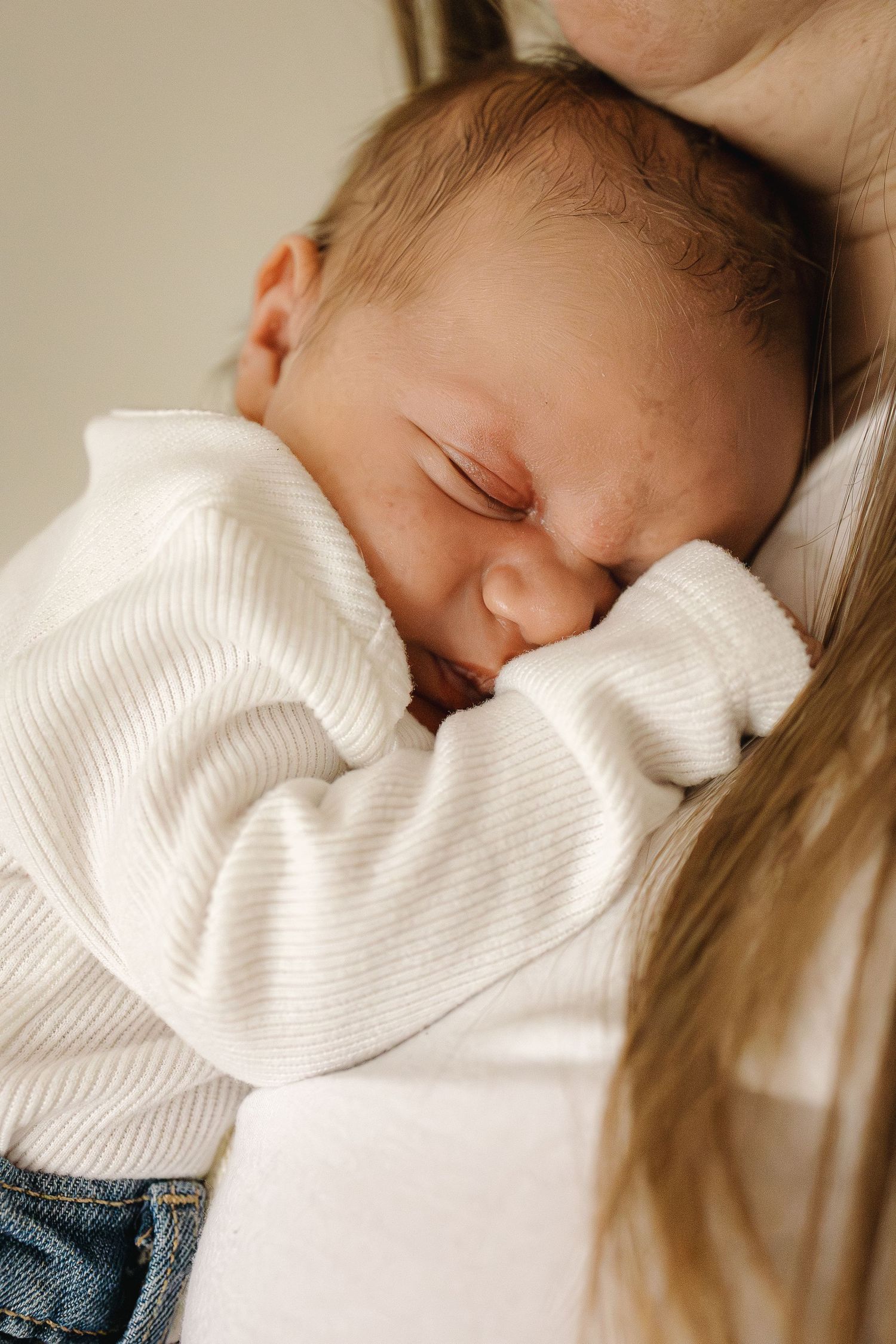 Newborn baby snuggled up under moms chin, sleeping