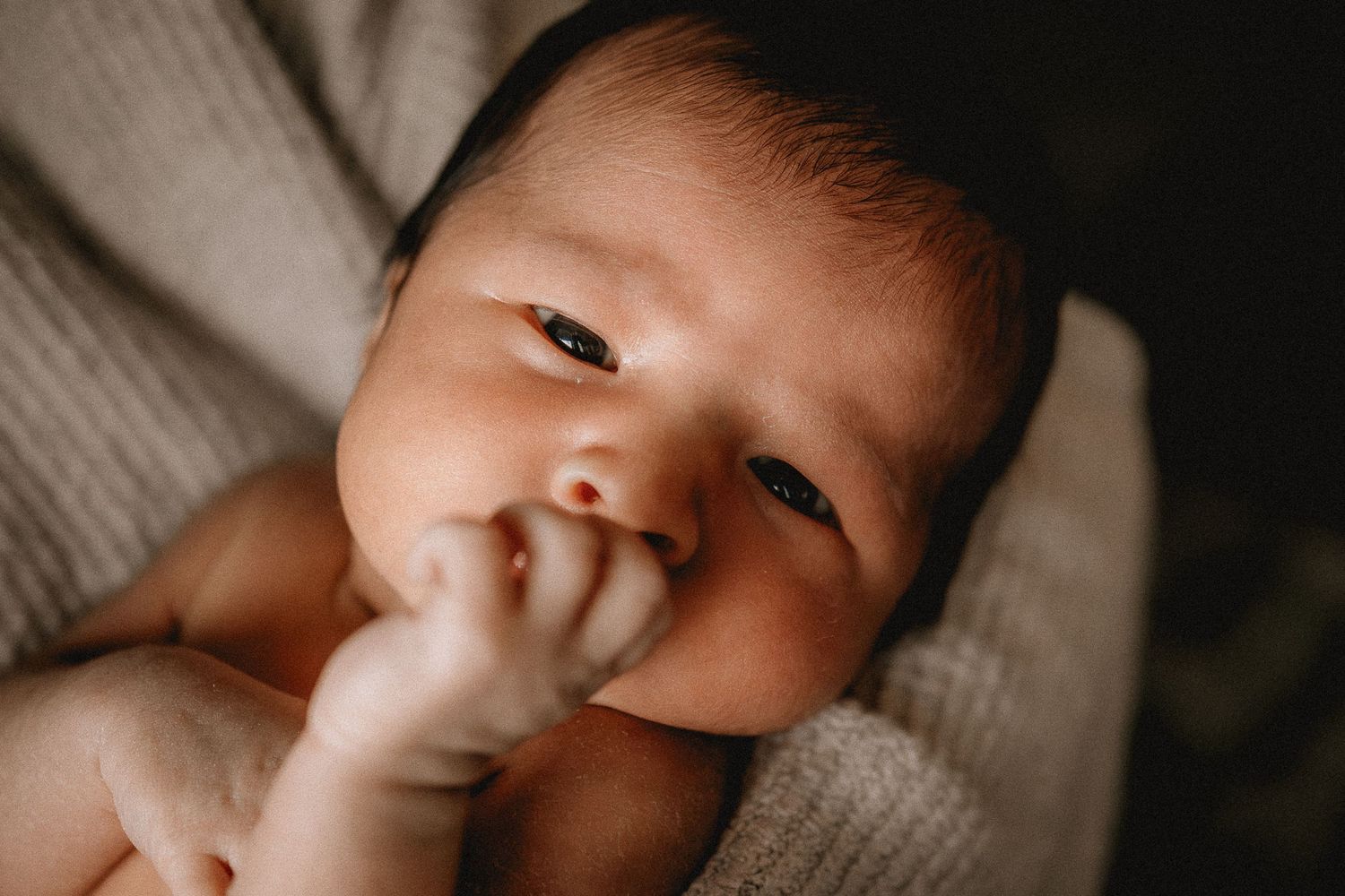 A sleeping baby rests peacefully in moms arms in warm natural lighting.