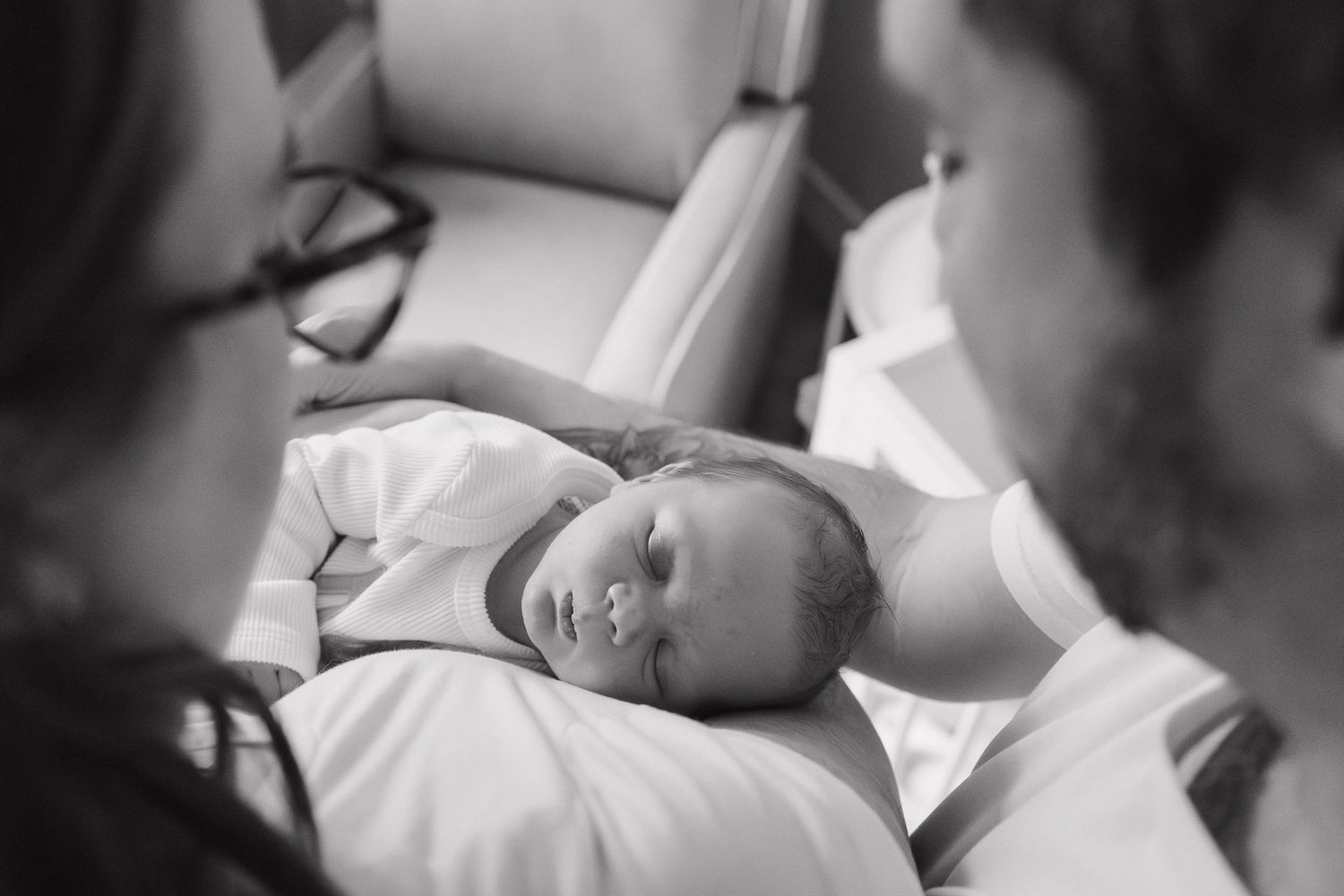 Black and white photo of mom and dad holding newborn baby during Calgary newborn session