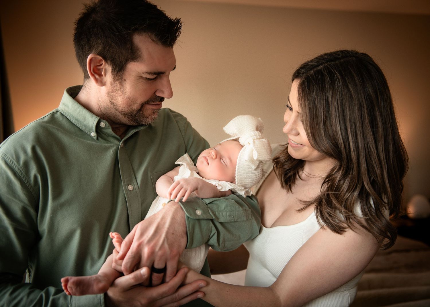 A tender moment between parents and their newborn baby in warm lighting.