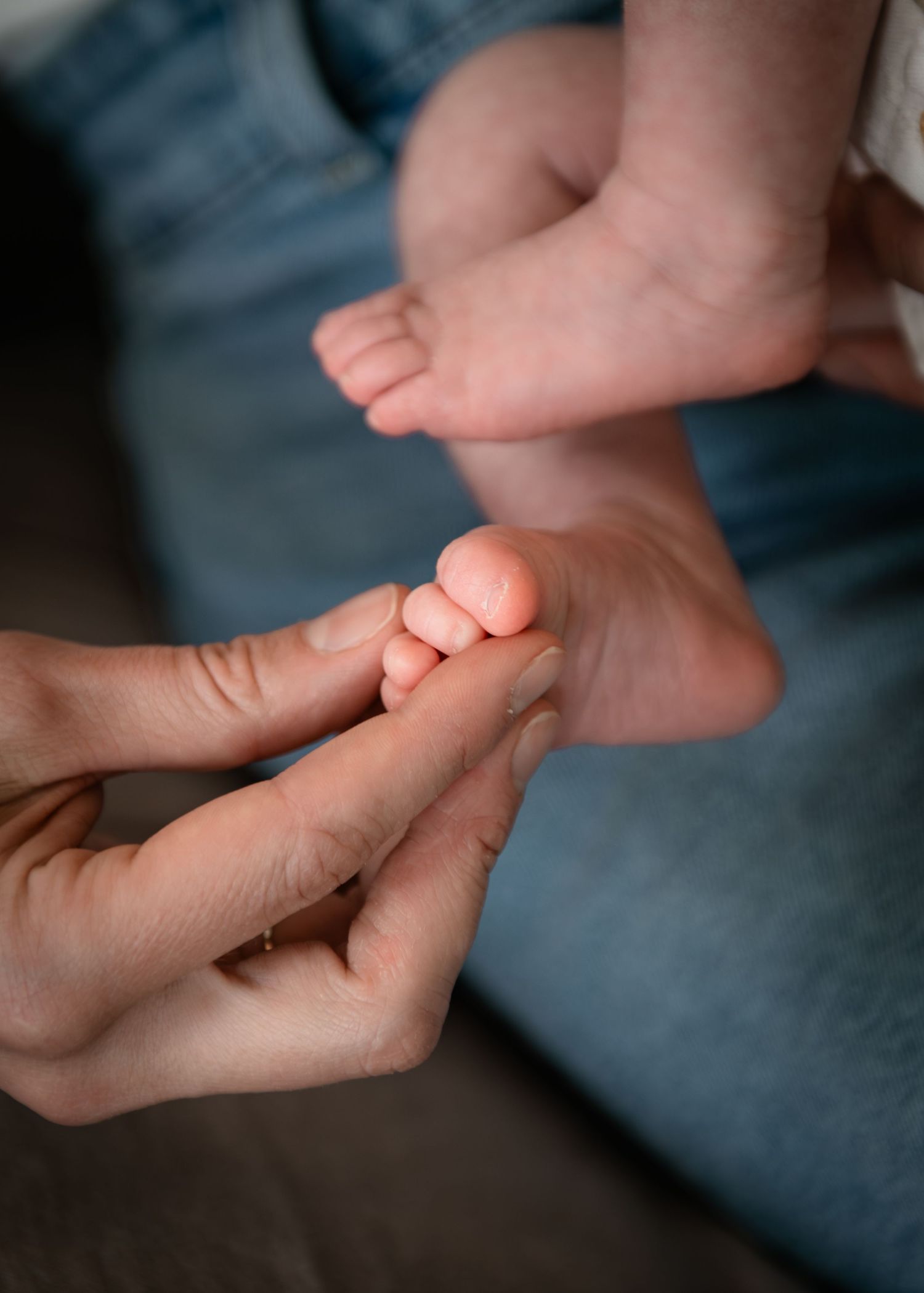 Calgary mom gently holding and massaging a newborn baby's tiny feet and toes closeup.