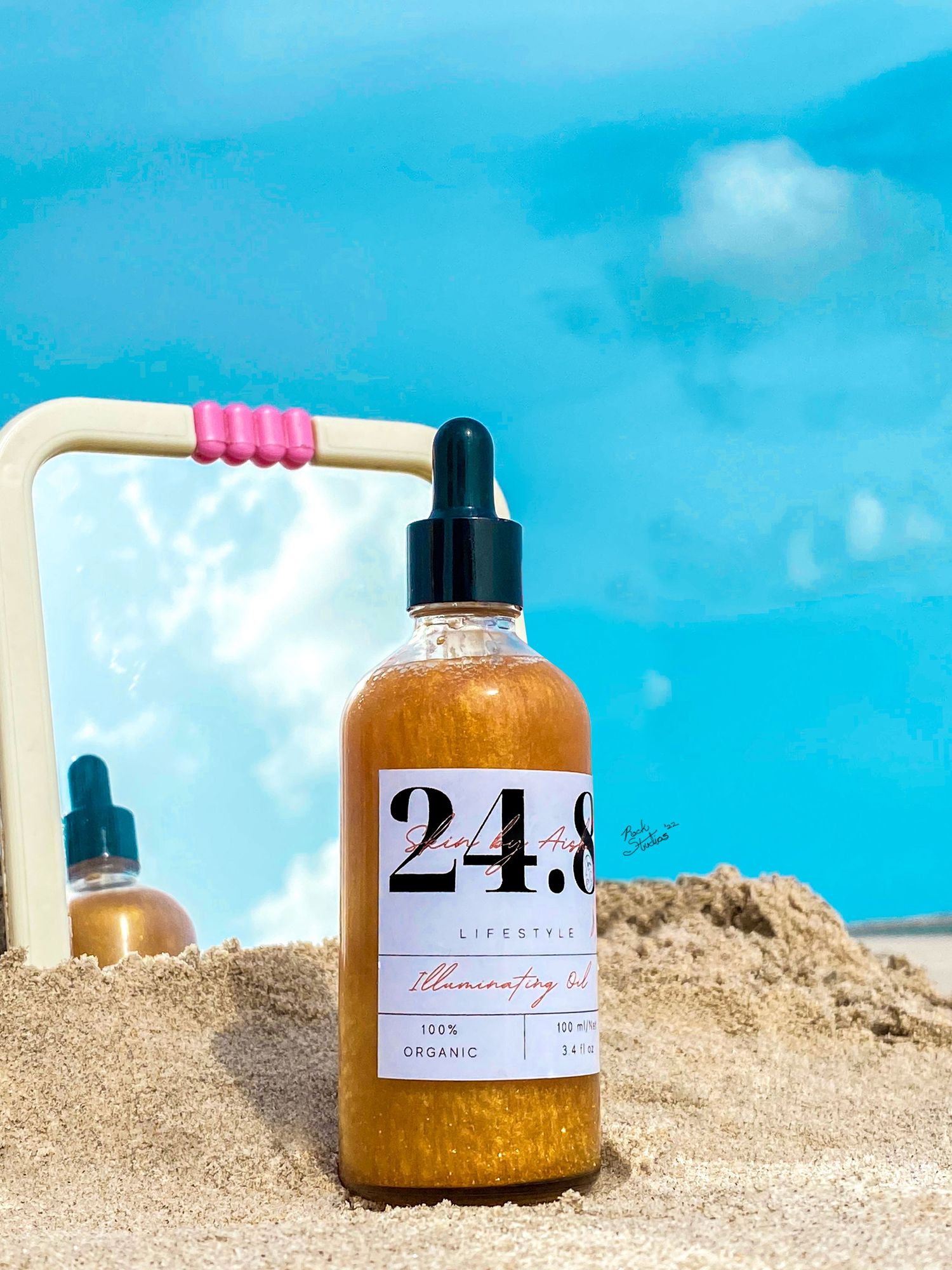 Editorial product shoot of 24.8 liquid gold oil on beach sand