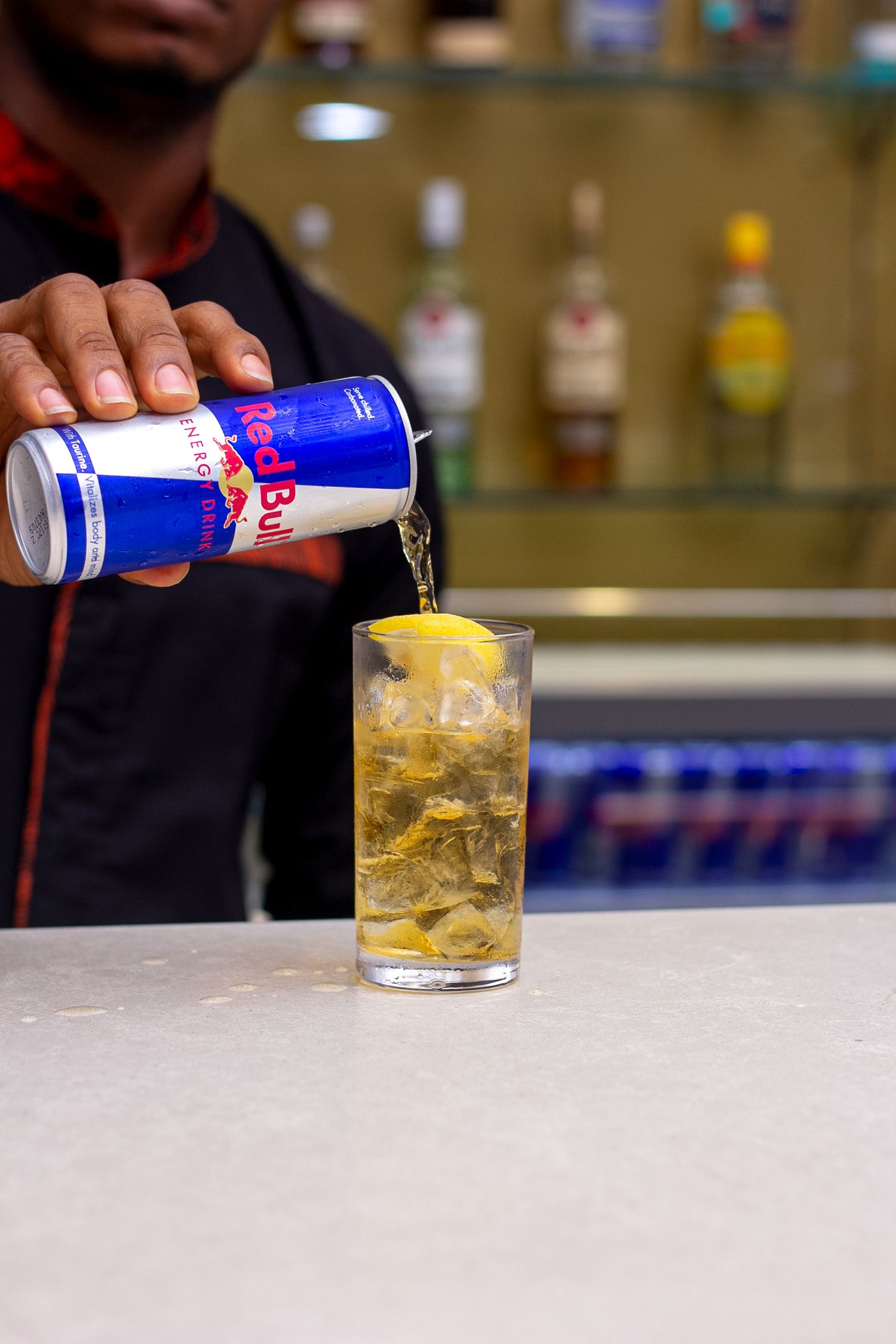 Redbull product shoot with a bartender pouring a can of Redbull into glass cup filled with ice and slice of lemon