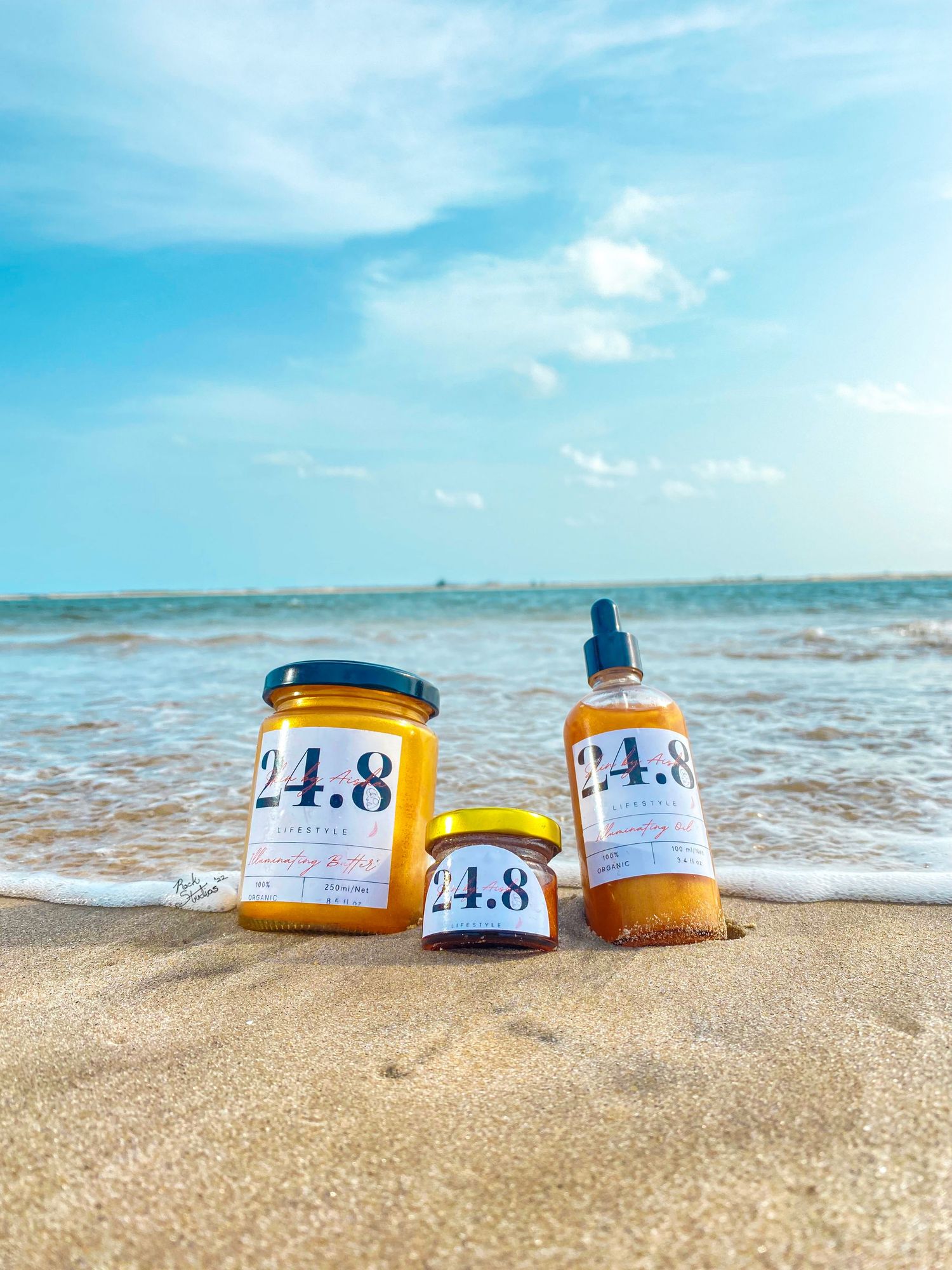 Editorial product shoot of 24.8 body scrub, lip balm and liquid gold oil at the beach