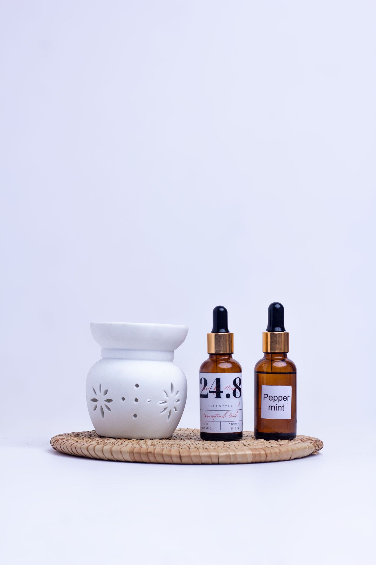 Catalog product shoot of 24.8 beard oils beside a ceramic prop on a ratan mat