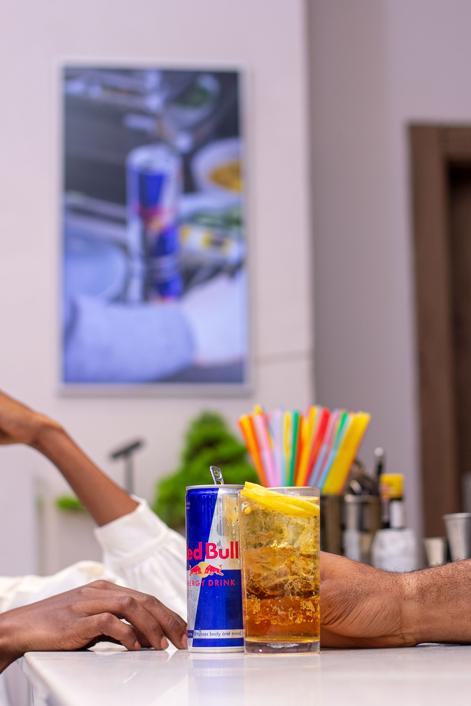 Redbull product photoshoot showing a bartenders hand serving a waiting customer with a Redbull electronic poster in the background