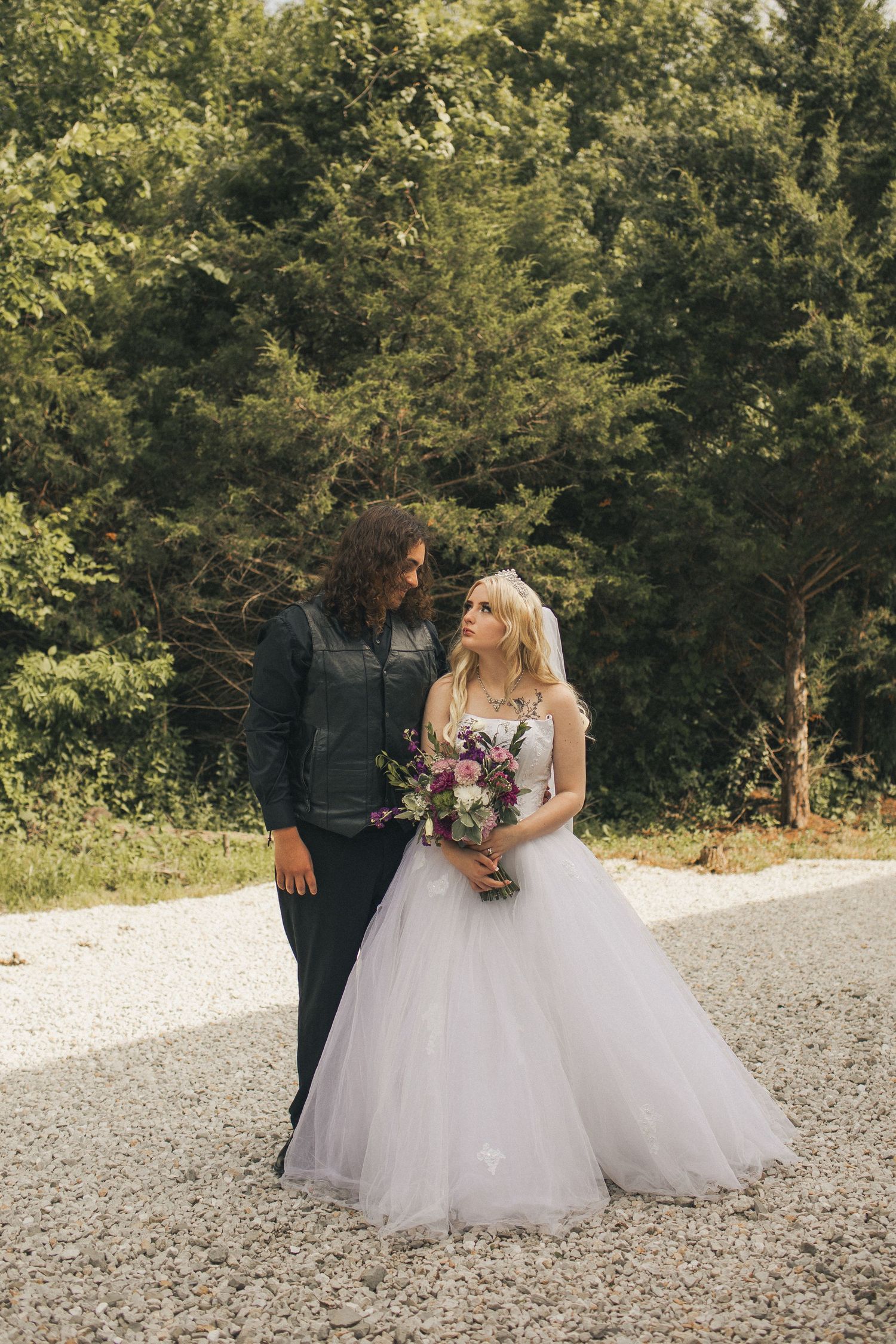 A young bride and groom walking toward the camera and looking at each other.
