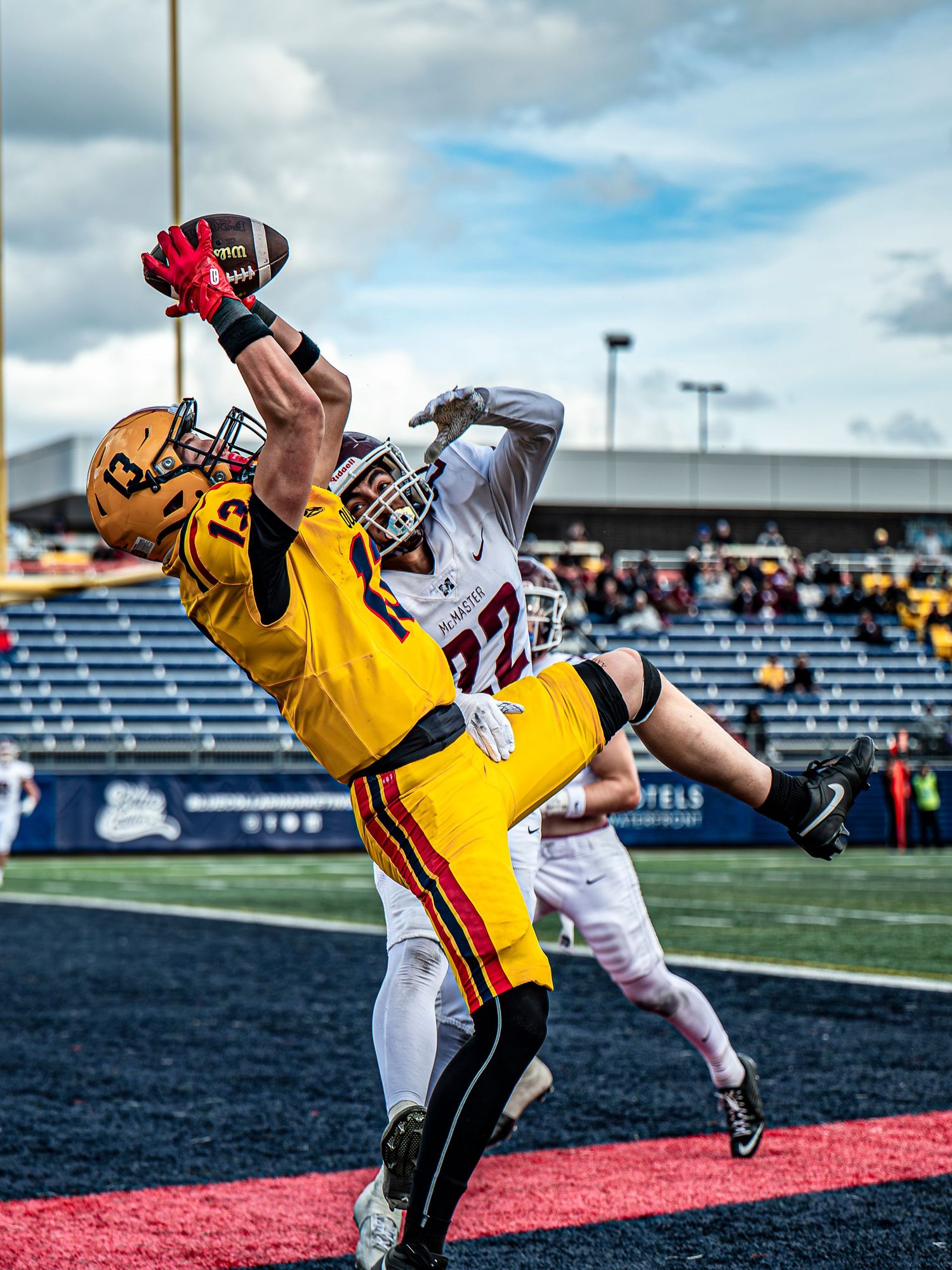 Football player in yellow uniform dives into end zone during game play.