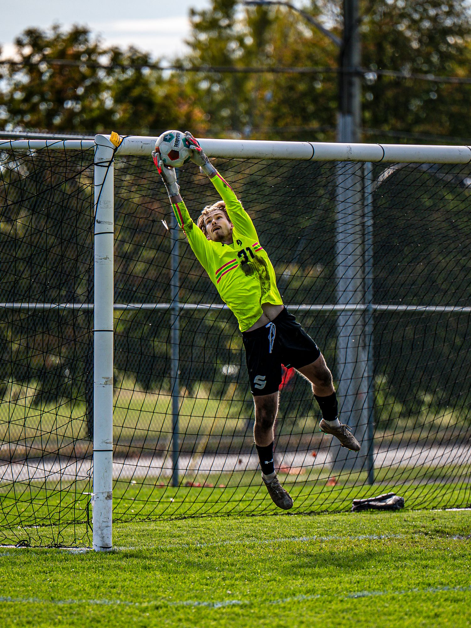 Soccer goalkeeper in yellow jersey makes diving save sequence at goal.