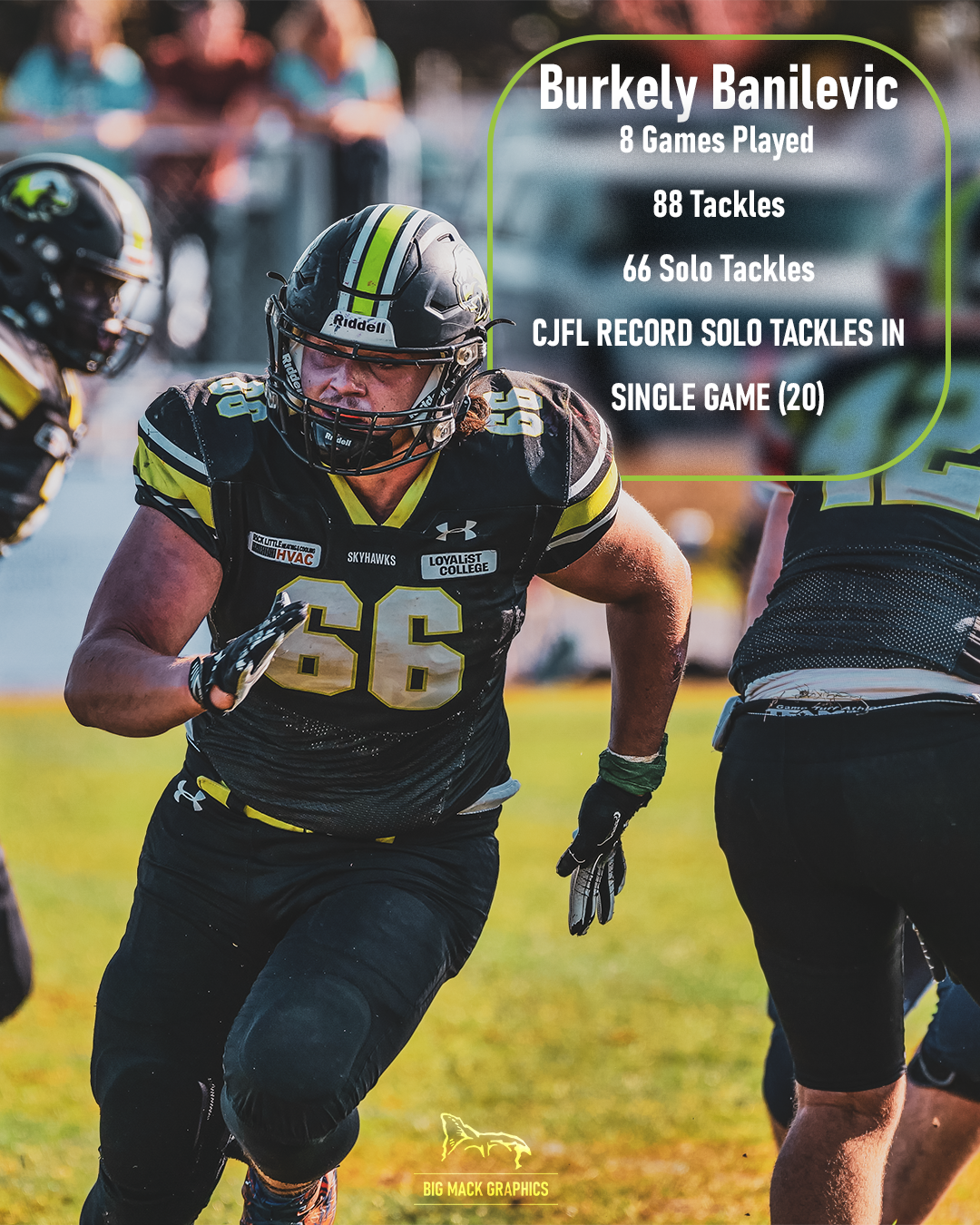 Football player in black uniform performs defensive stance on grass field during game action.