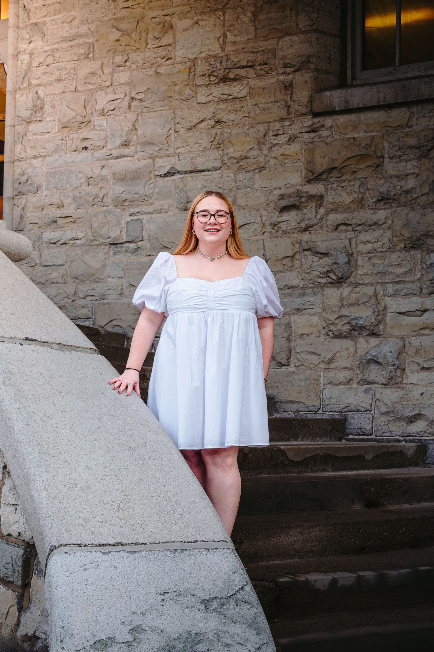 A series of photos showing someone in a white summer dress posing against a rustic stone wall backdrop.