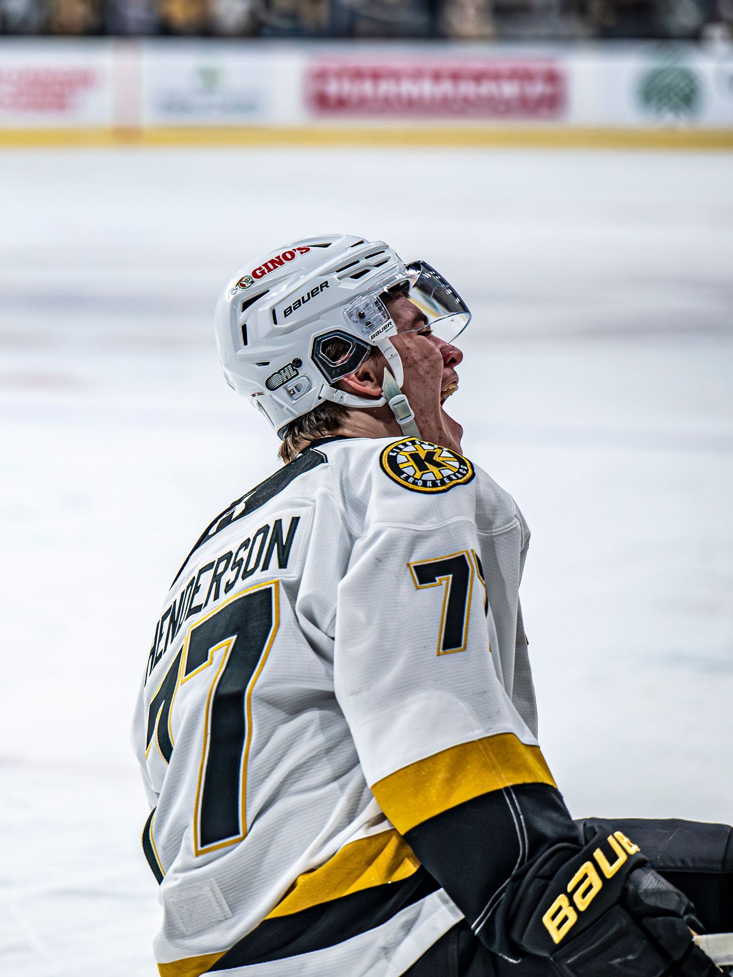 Hockey player in white jersey looks up during game on ice rink.