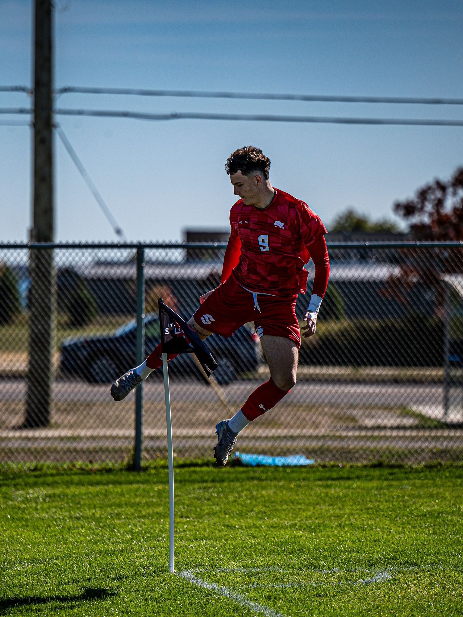 Player in red uniform performs diving catch on grass field during sports game.