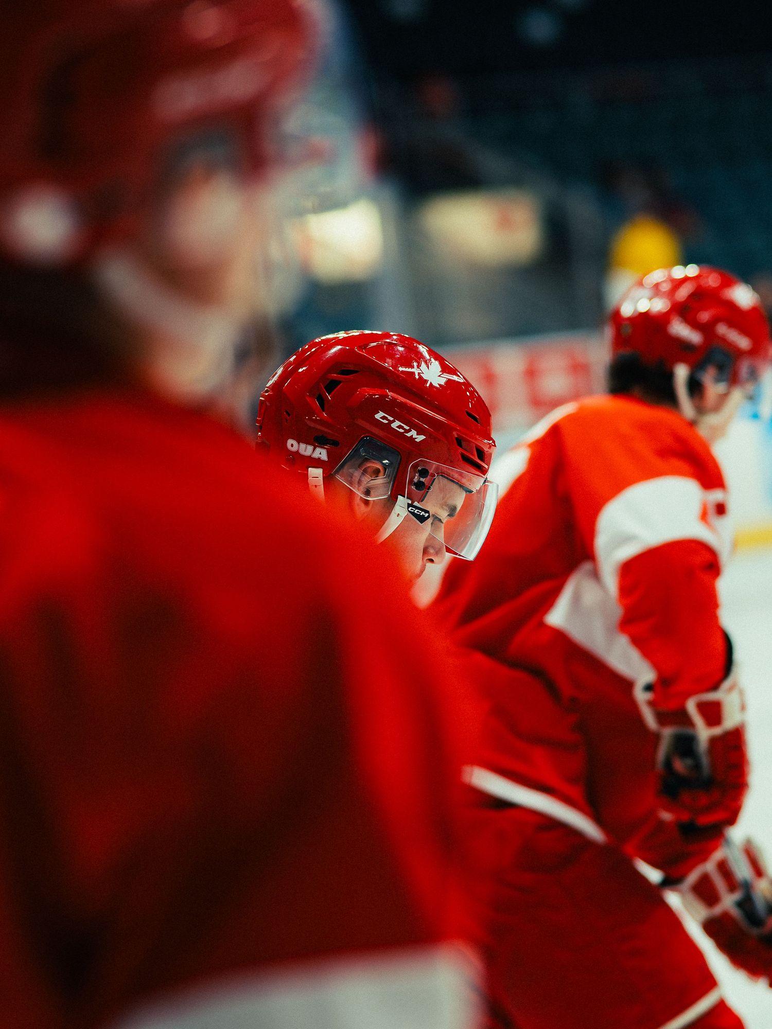 Hockey players in red jerseys sit on the bench during a game, creating a blurred motion effect.