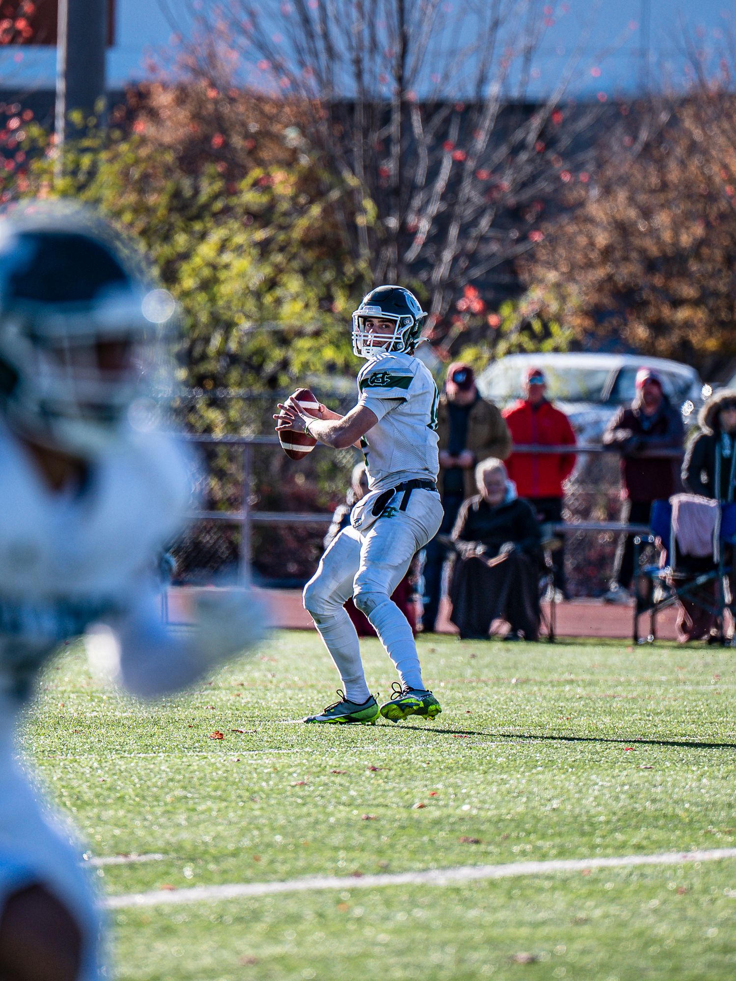 Football player in white uniform runs play sequence on sunny autumn field.