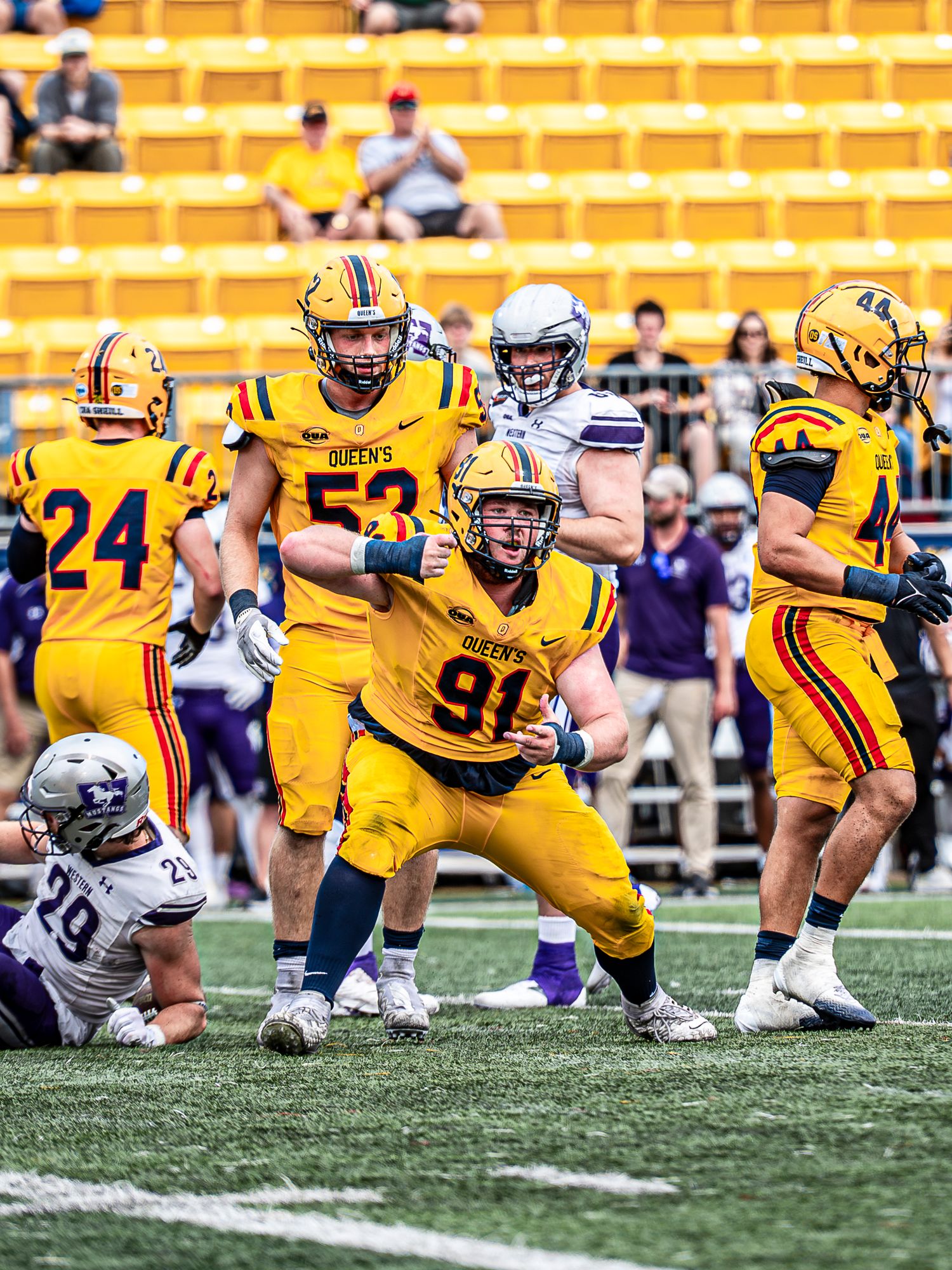 College football players in yellow uniforms diving and making tackles during an intense game on the field.