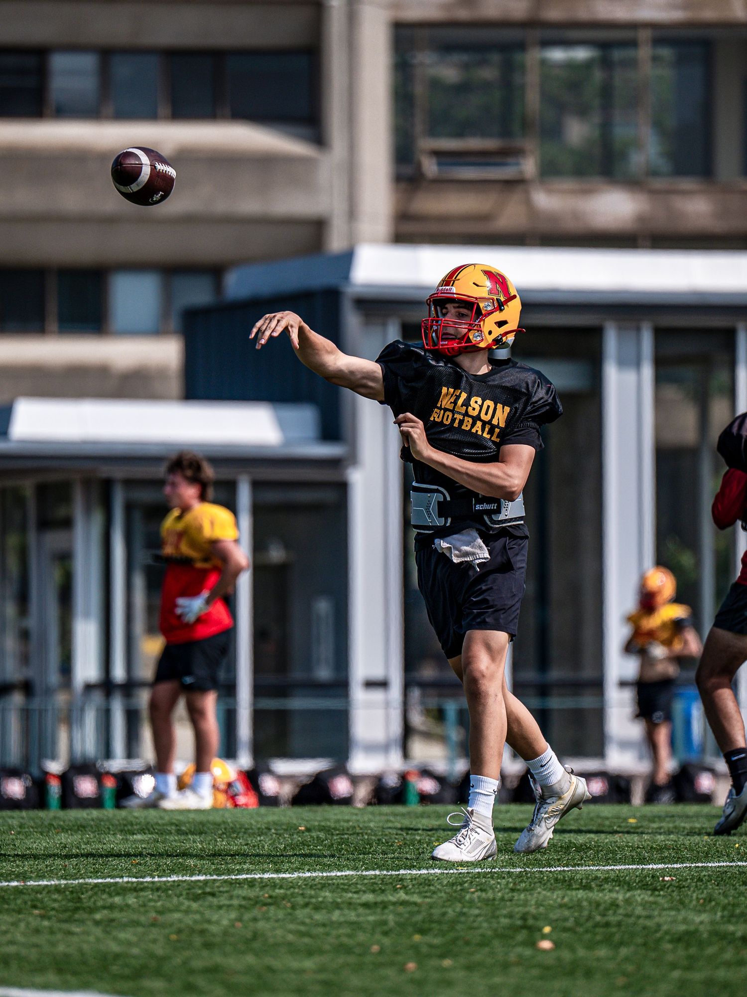 Football player practices punting drills on an artificial turf field.