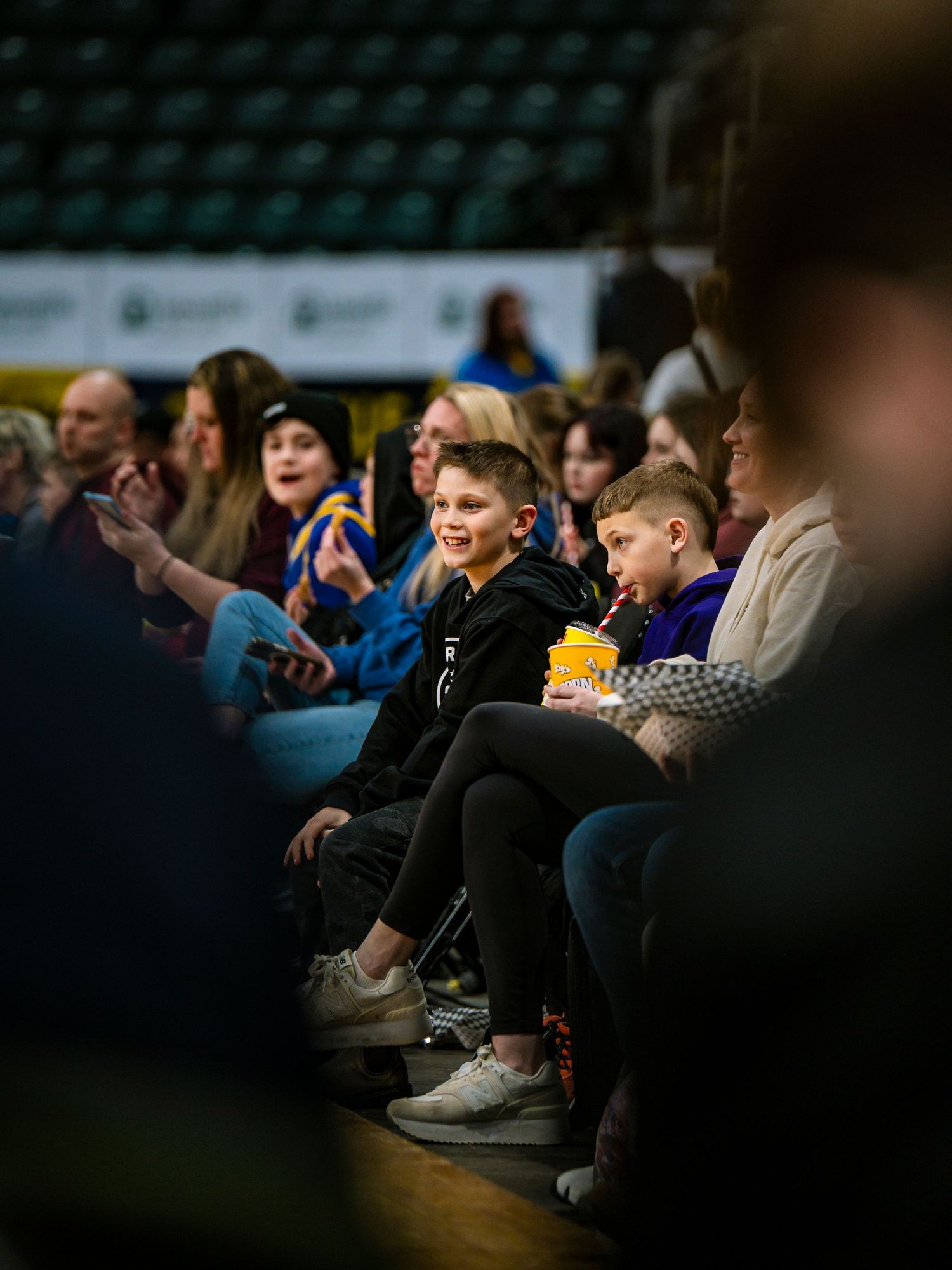 Audience members seated in rows watching intently during a dark indoor performance or event.