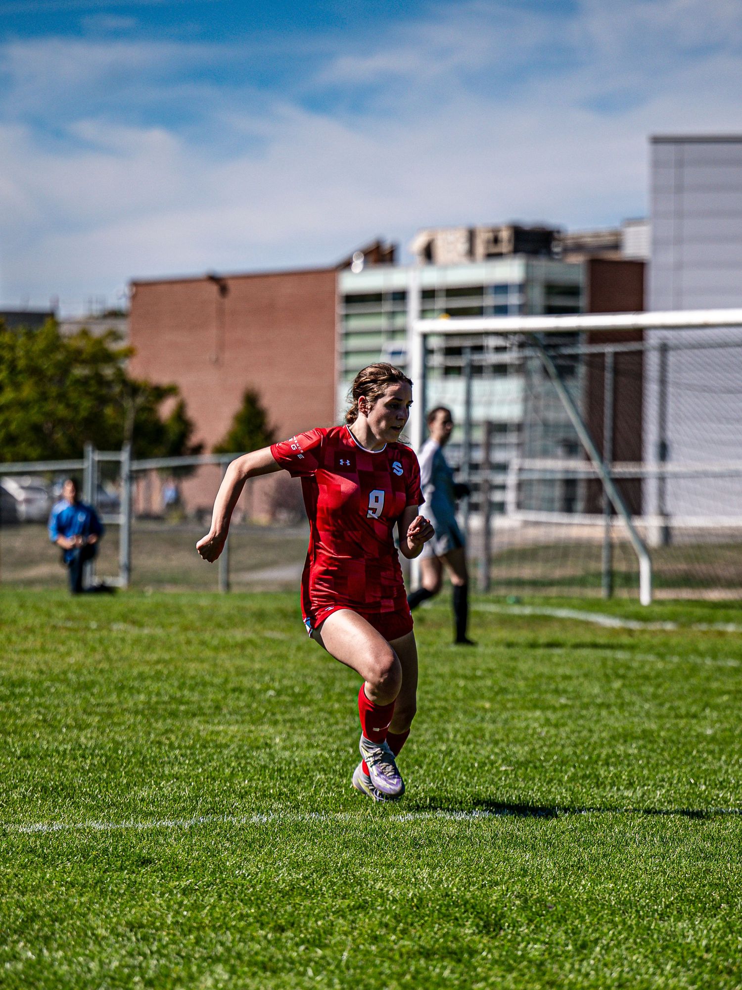 Soccer player in red jersey sprints across field during competitive match.