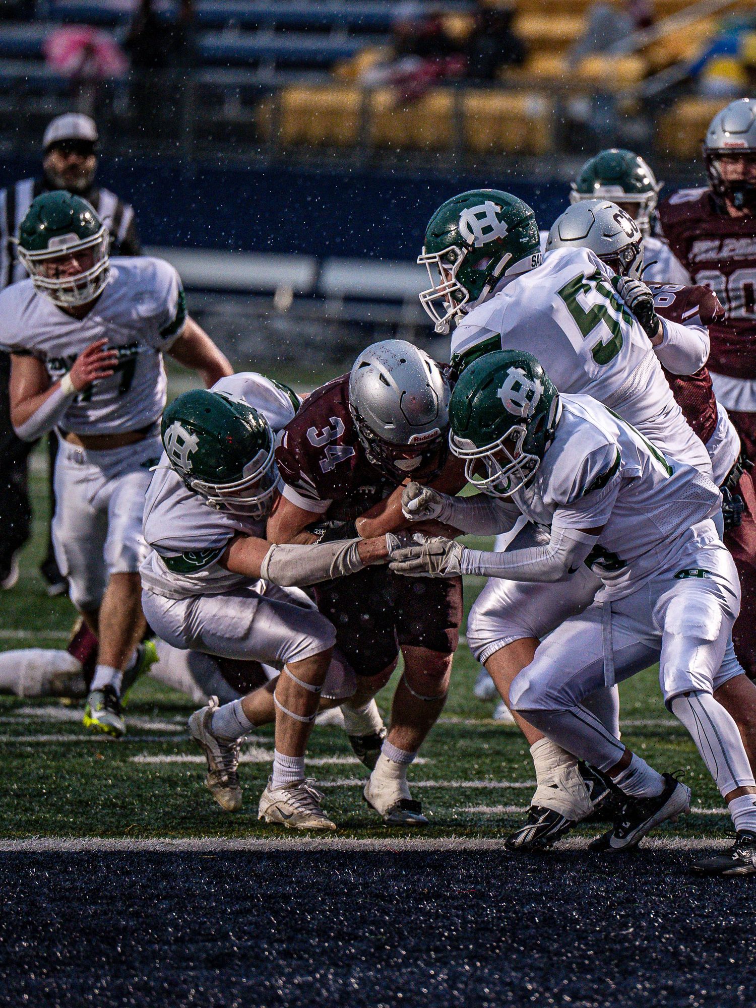 Football players in white and green uniforms line up in formation on the field during a game.