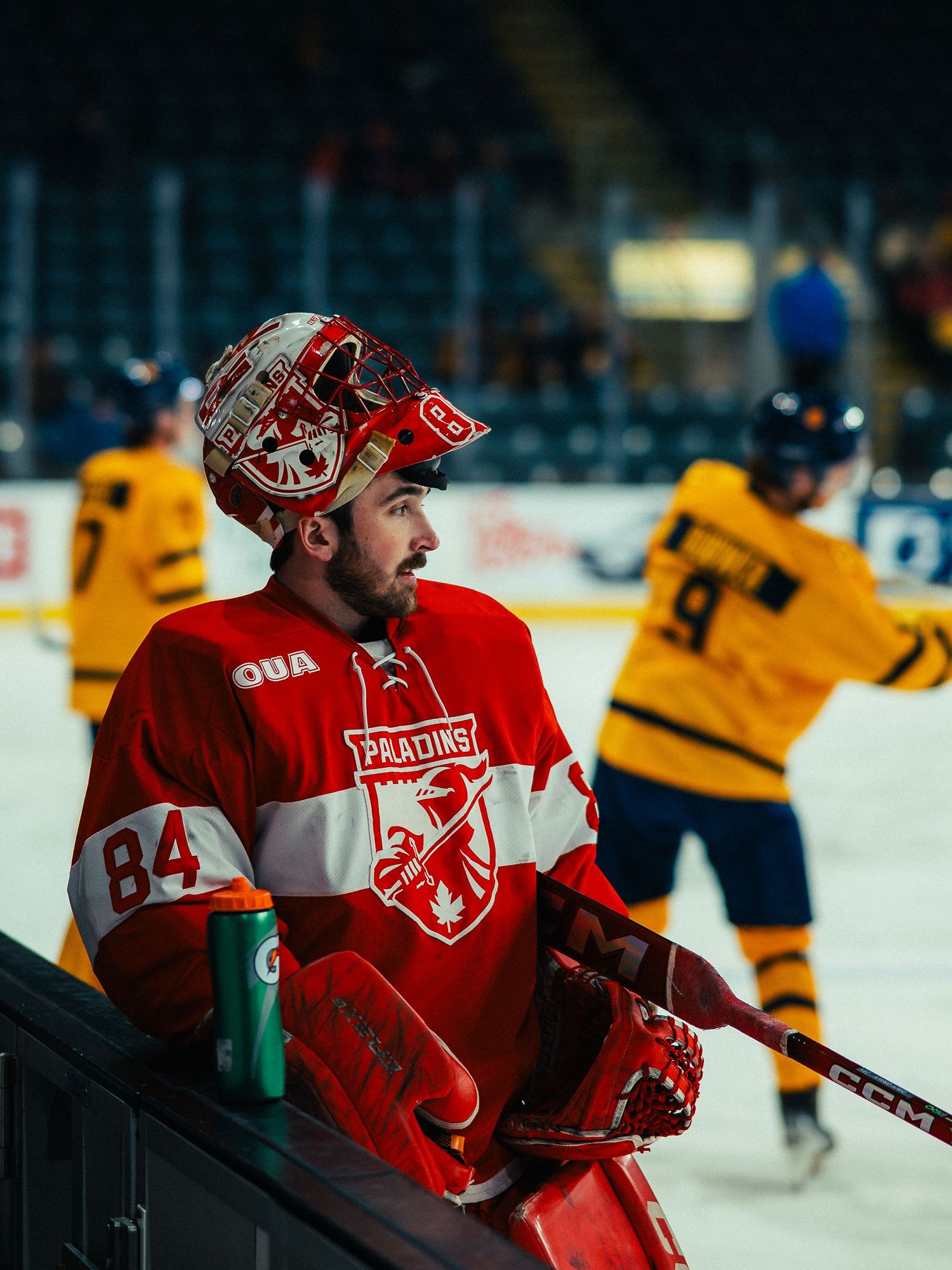 Hockey players in red and yellow jerseys compete during an intense match on the ice rink.