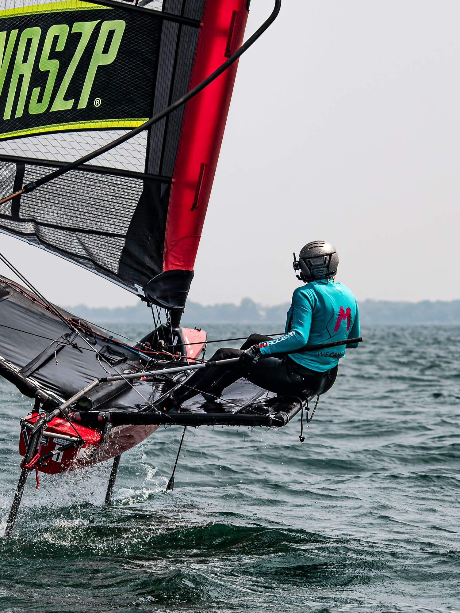 High-performance sailboat hydrofoiling across choppy waters with bright green and red accents visible in action sequence.