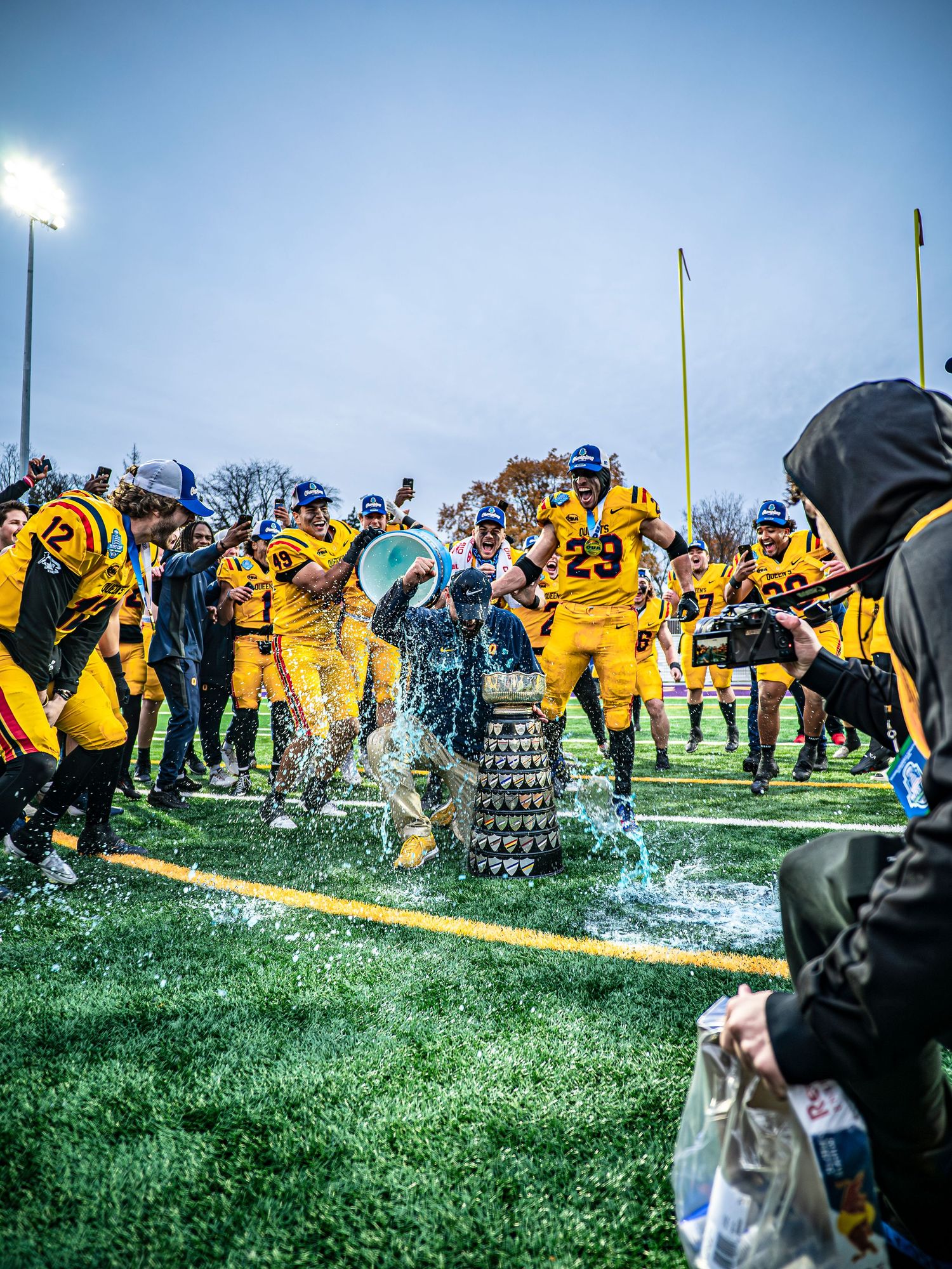 Team in yellow uniforms celebrates victory on field with water splashing celebration.