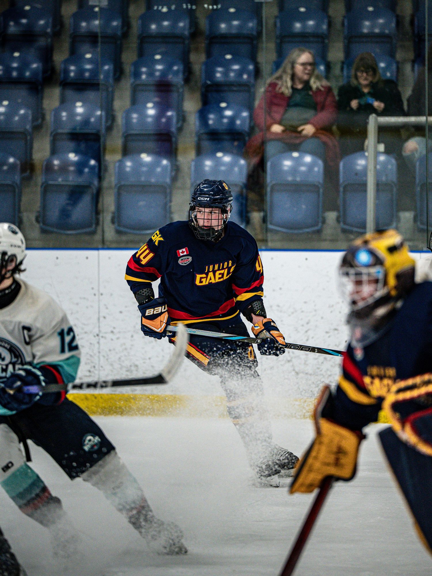 Ice hockey players in yellow and dark uniforms battle for the puck creating sprays of ice during an intense game.