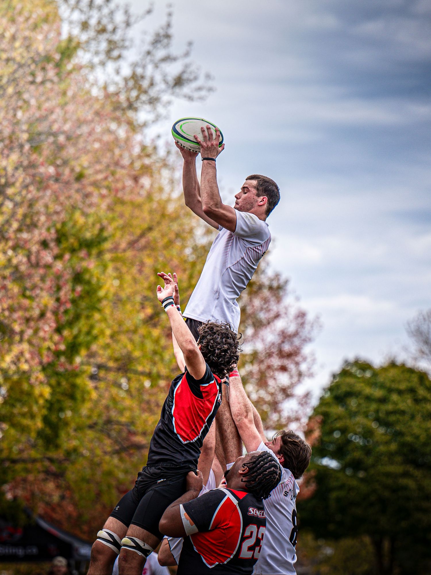 Rugby players compete for the ball in a lineout jump during match play.