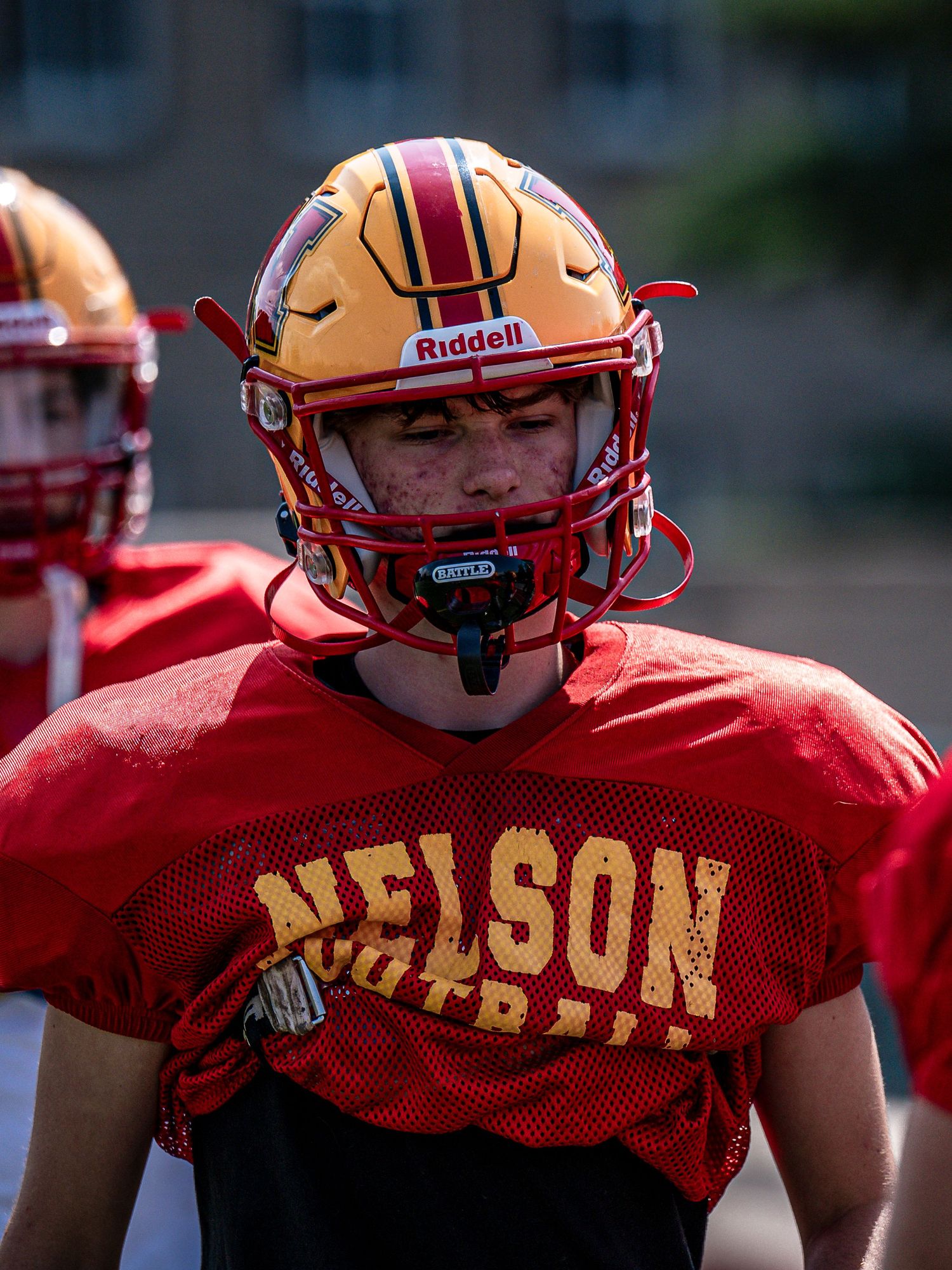 Close-up view of red and gold football helmets with Nelson team branding.