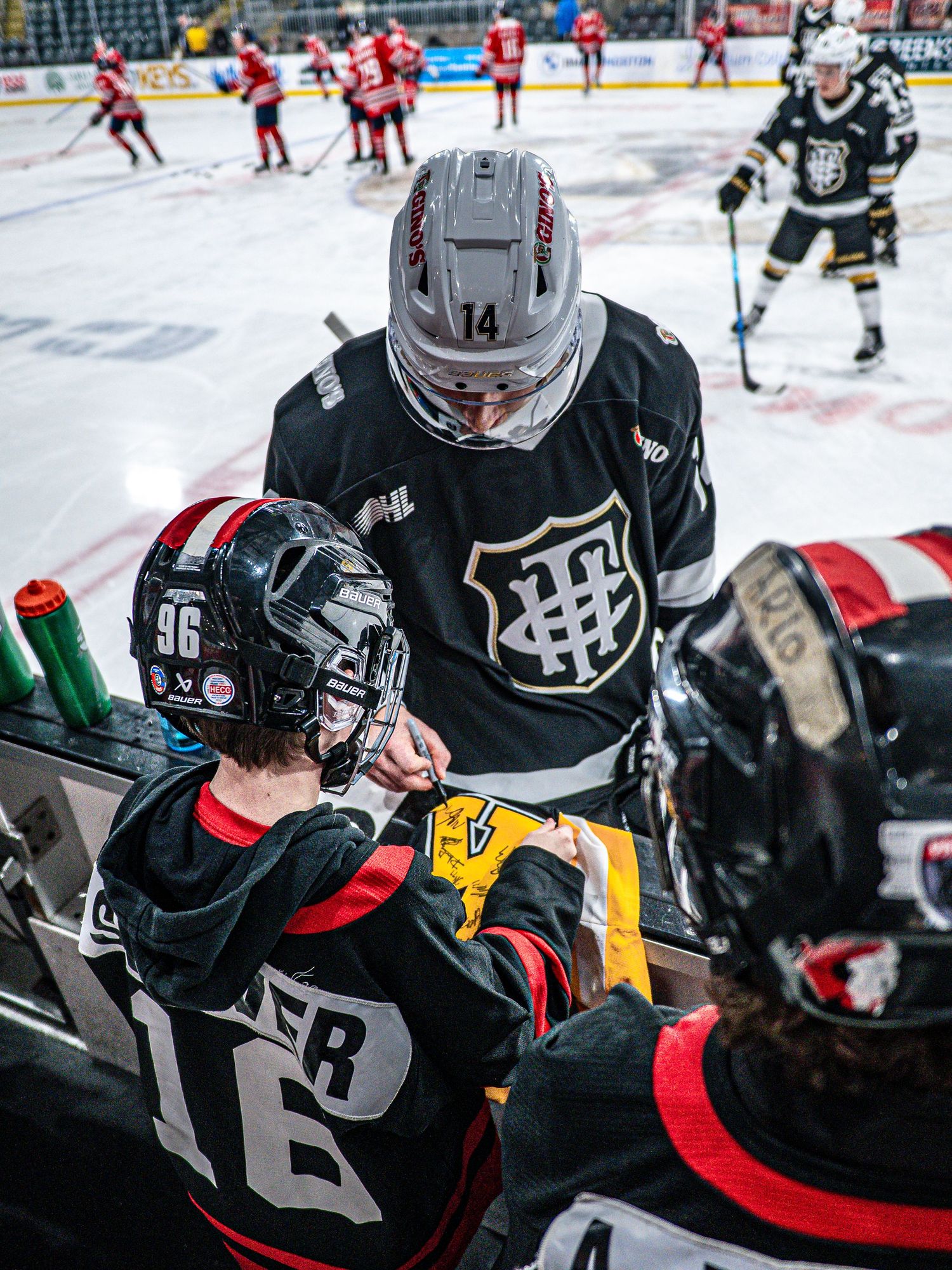 Ice hockey players in black and red jerseys compete intensely during a match.