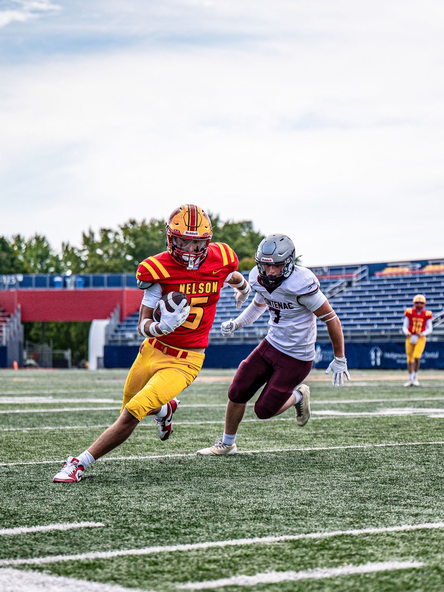 Football players in yellow and white uniforms compete during a game on an artificial turf field.