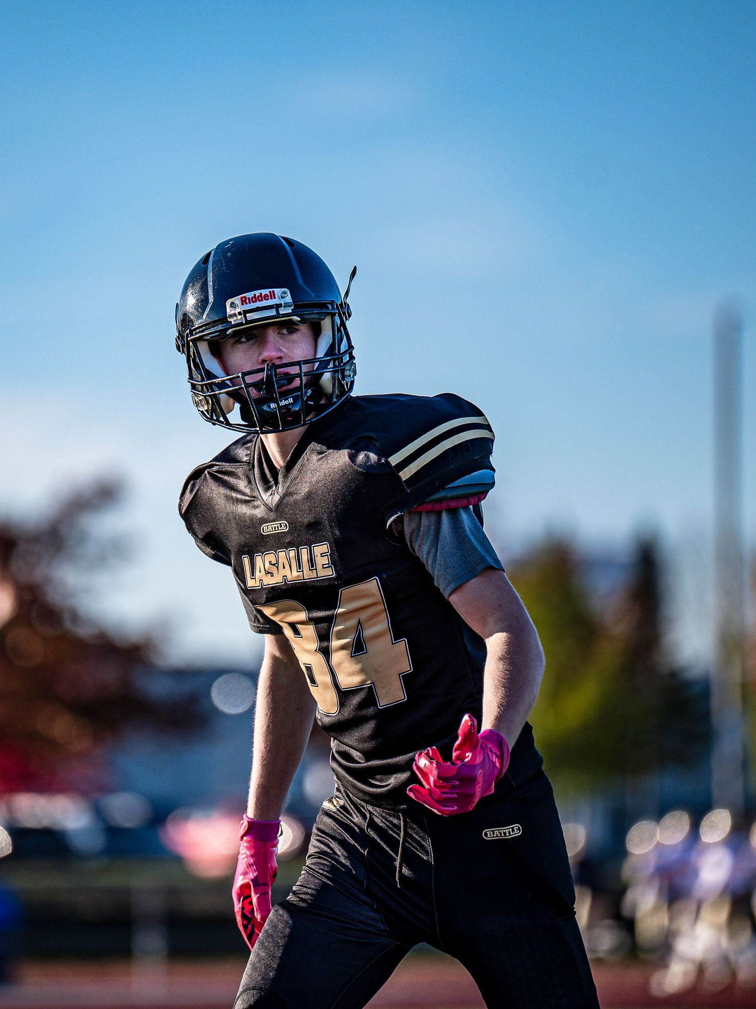 Football players in dark uniforms prepare for play during evening game.