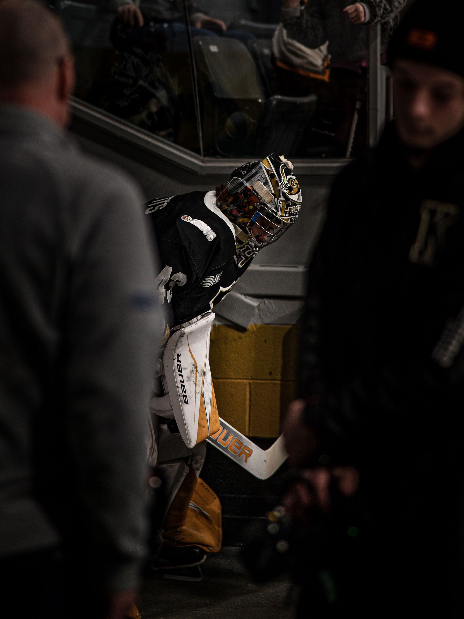 NHL hockey goalie in black and gold uniform makes a dramatic save during an intense game moment.