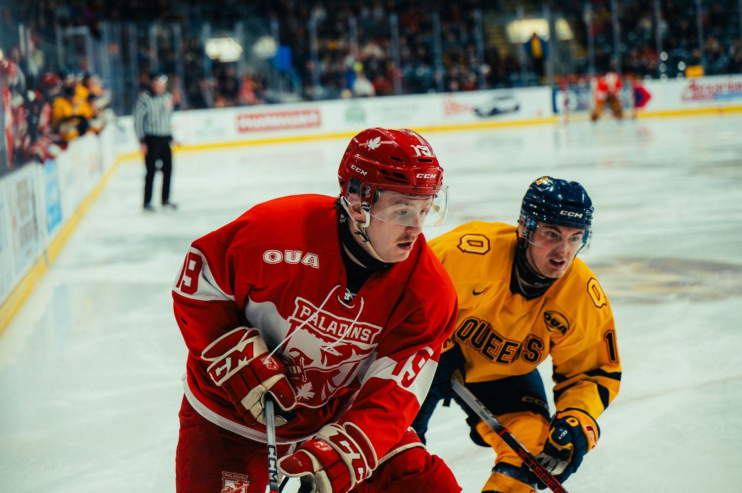 Ice hockey players in red and yellow jerseys battle for the puck during an intense game on the rink.