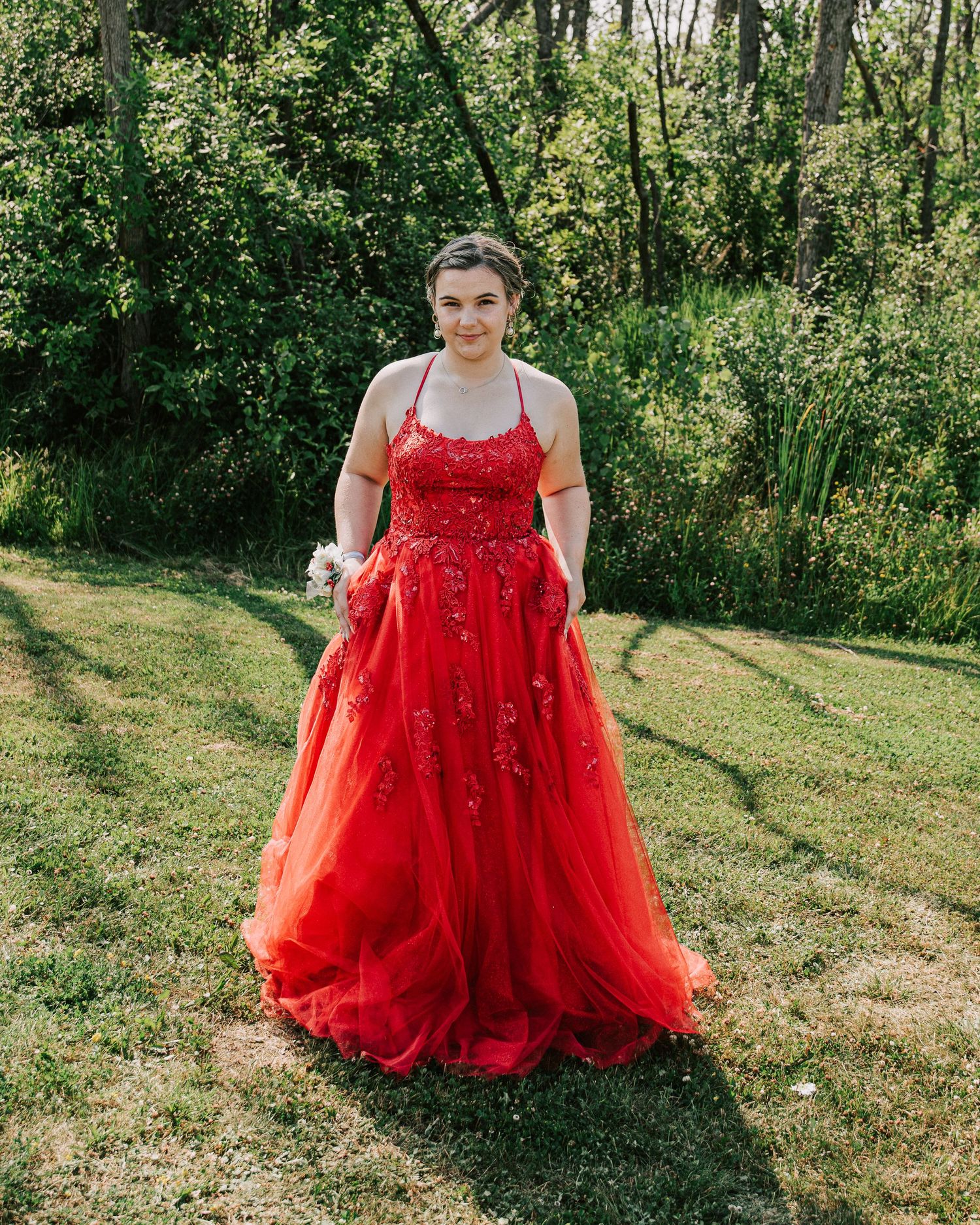 A red tulle ballgown with sequins sparkles in an outdoor garden setting across multiple poses.