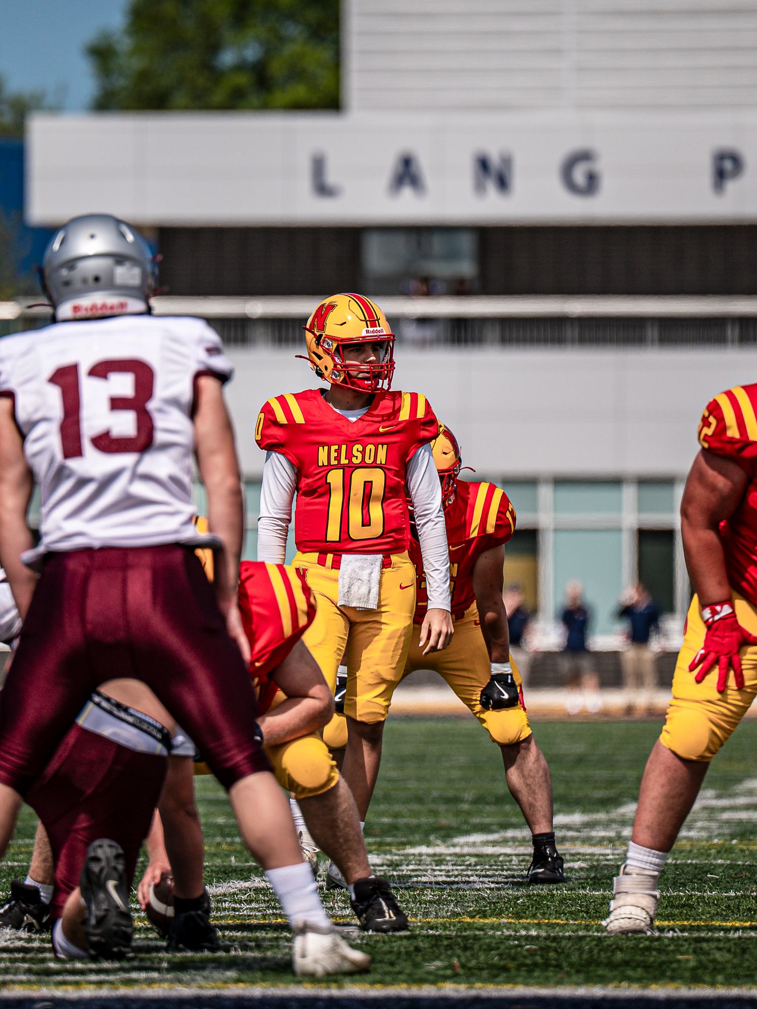 Football players line up at the line of scrimmage wearing yellow and maroon uniforms during a game.