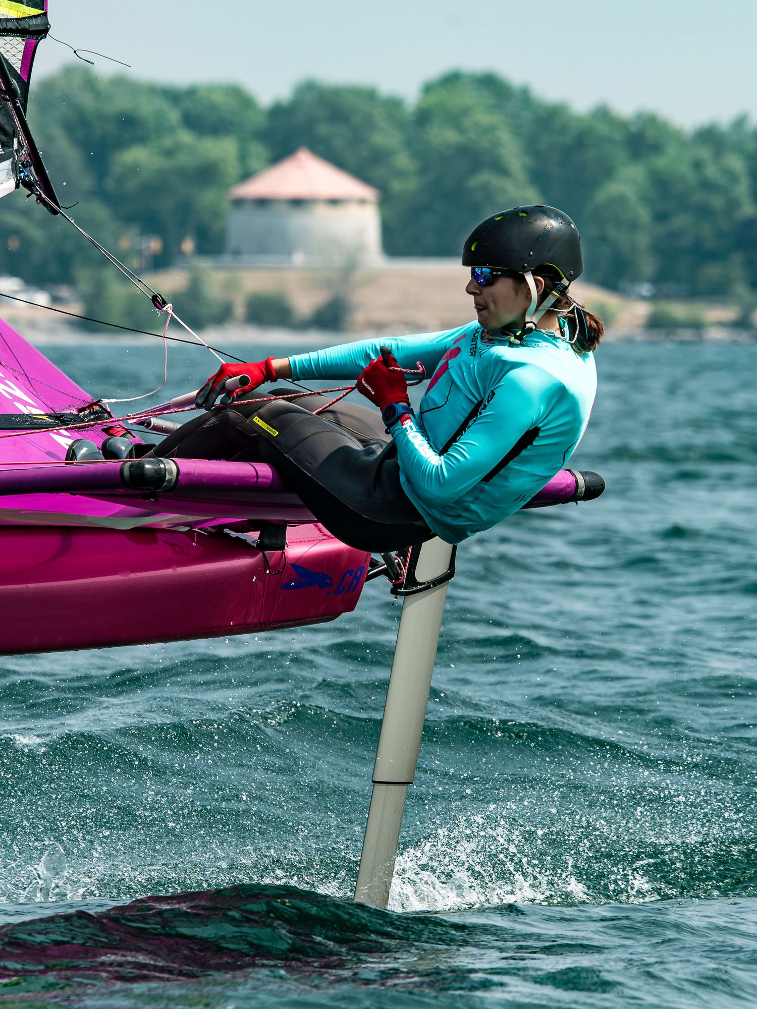 A sequence of action shots showing a kitesurfer in a teal wetsuit performing tricks on a pink board over choppy water.